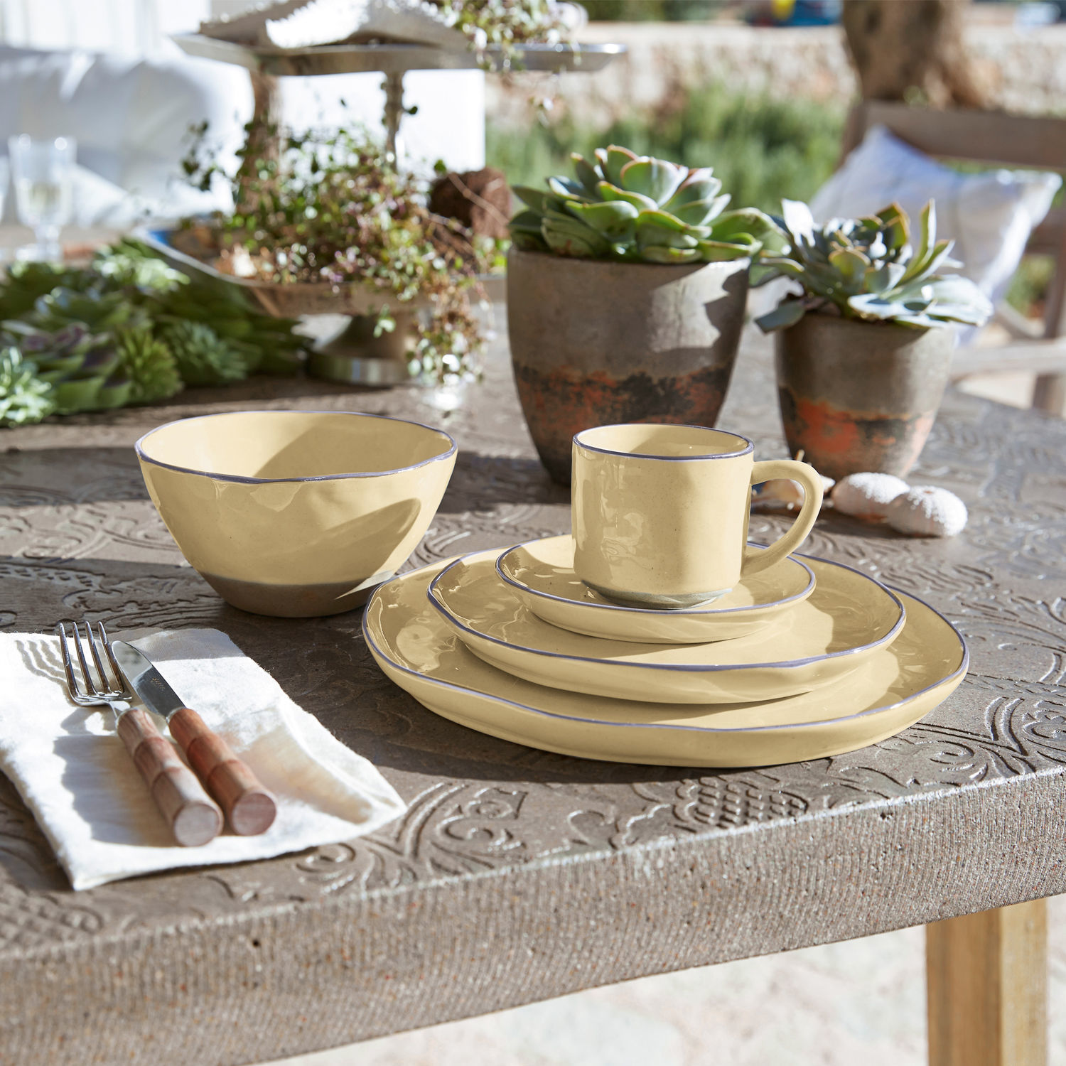Set di 30 stoviglie Biarré Set di stoviglie in ceramica crema con bordo blu su tavolo rustico decorato con piante grasse