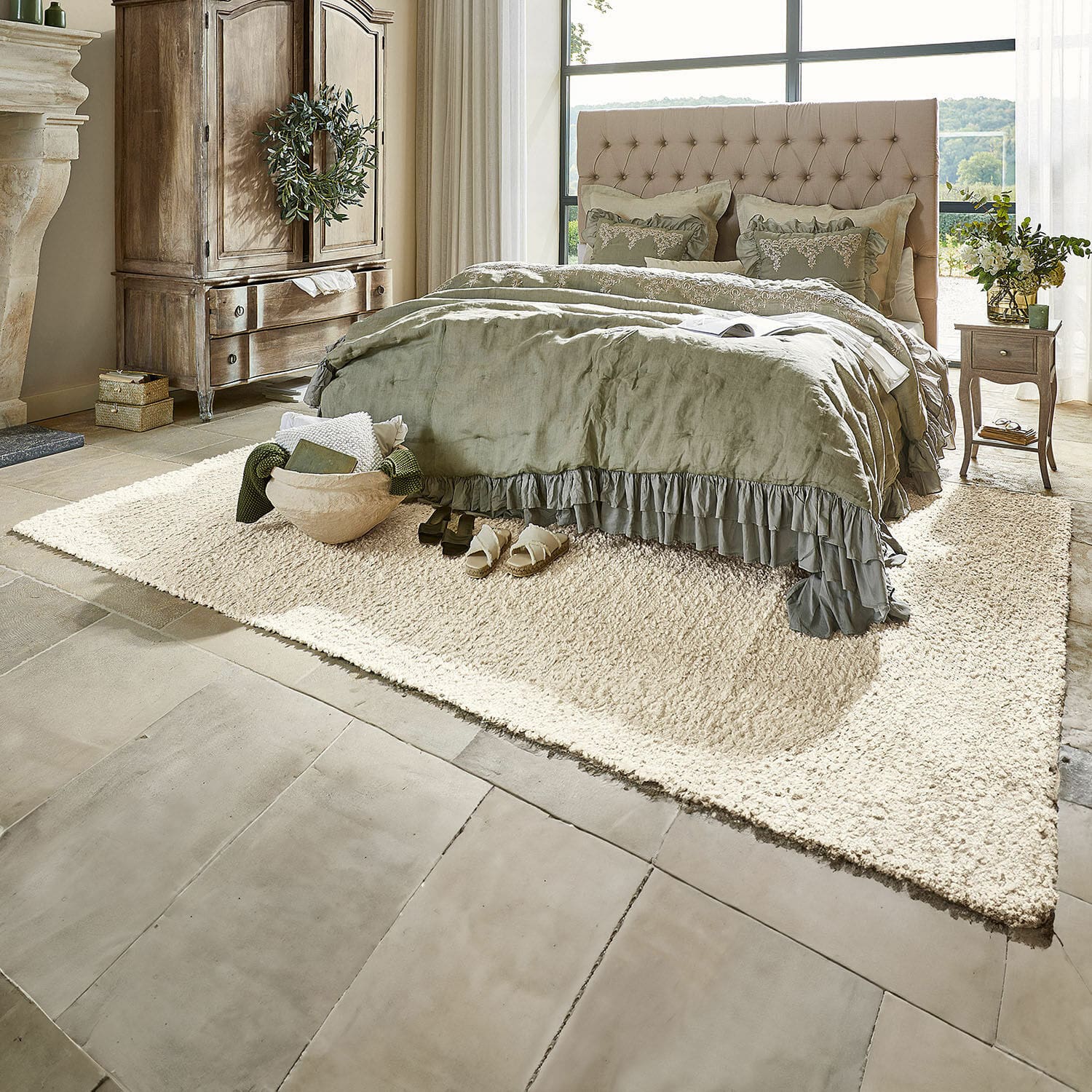 Tappeto Wodaha Camera accogliente con letto beige imbottito e biancheria verde su tappeto crema in materiale morbido