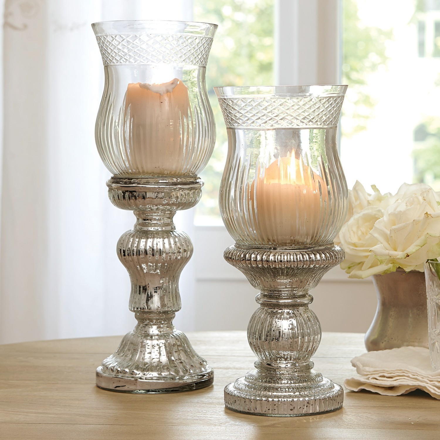 Coppia di portacandele Luisant Due portacandele decorativi in vetro con effetto argento invecchiato su tavolo in legno in ambiente luminoso