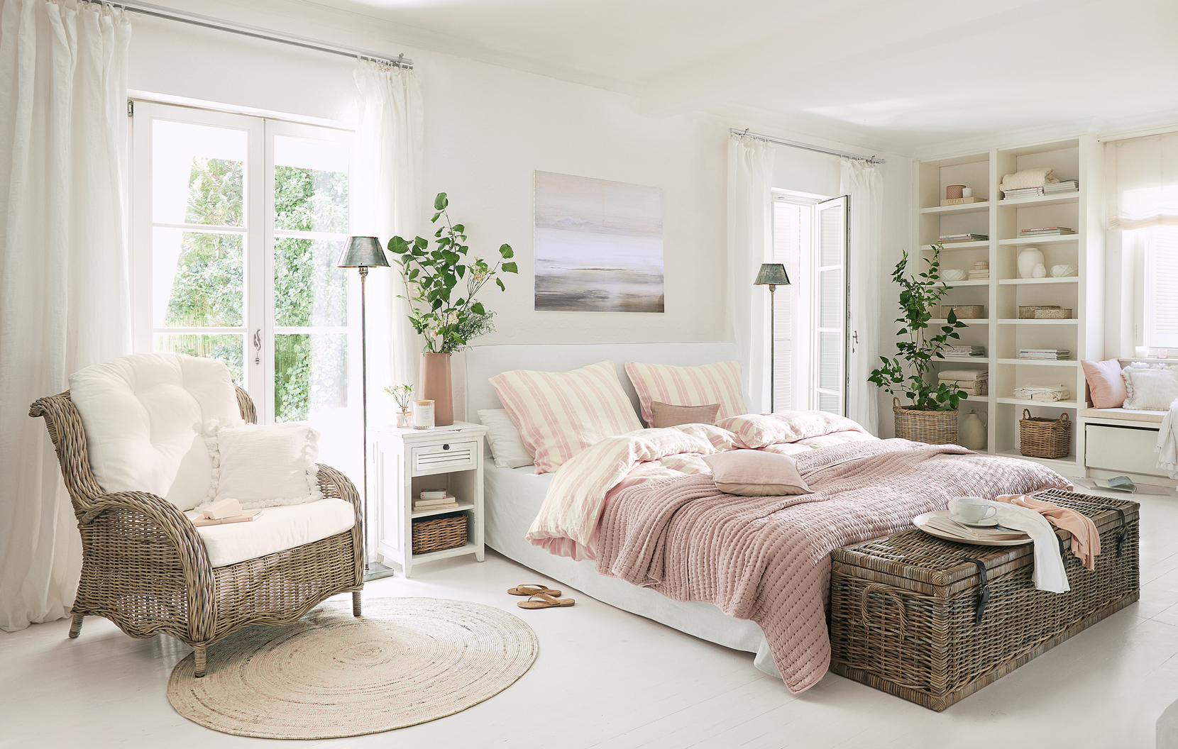 Camera da letto accogliente in stile country con poltrona in vimini e coperta rosa sul letto