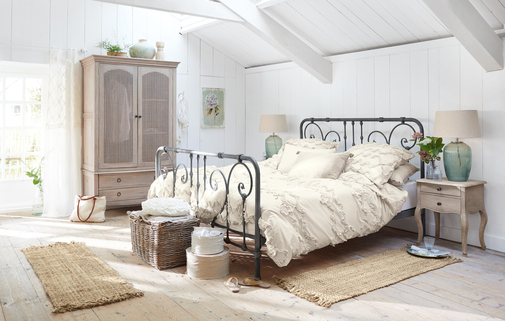 Camera shabby chic con letto in metallo nero e biancheria da letto crema in cotone, accessori naturali