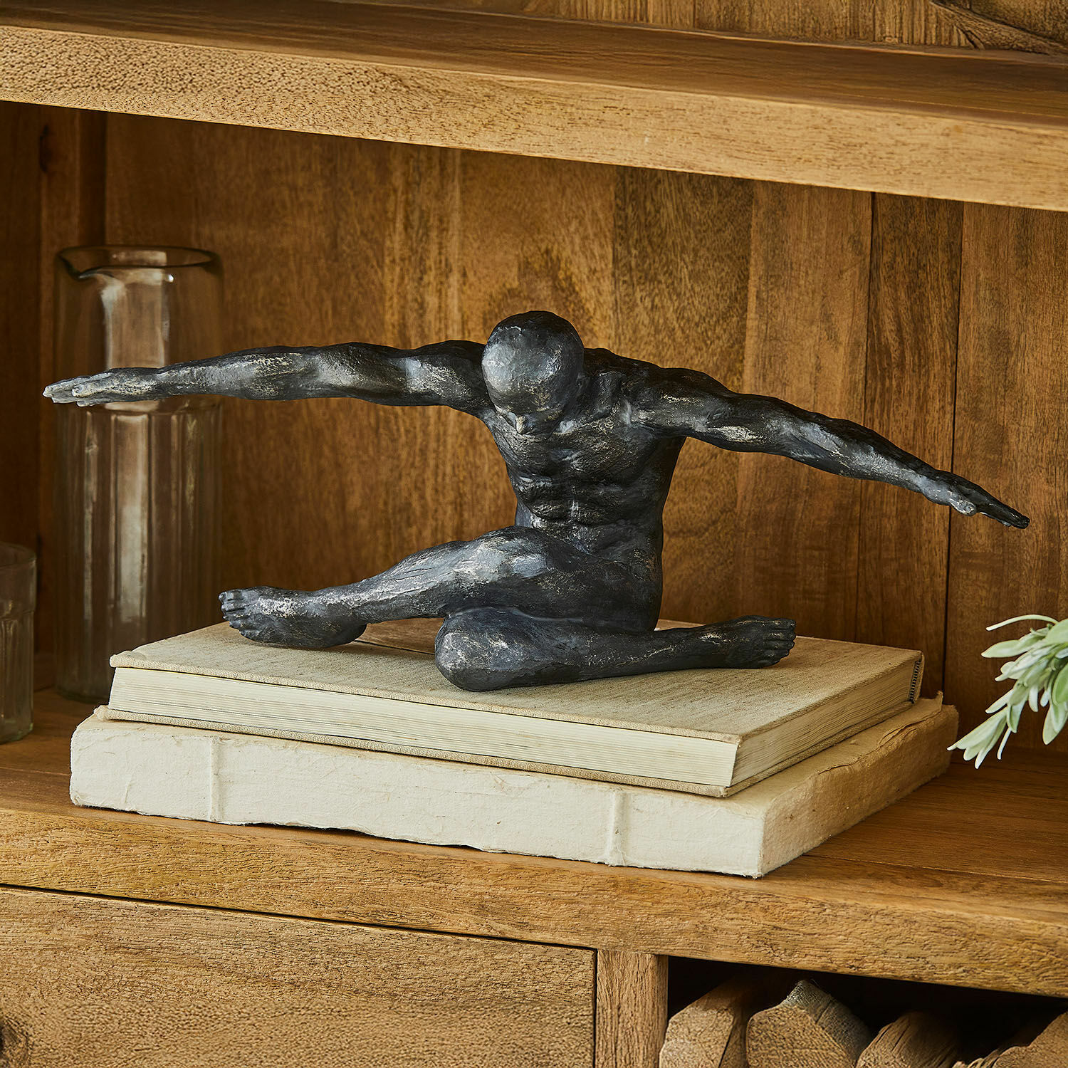 Statuina Smitty Scultura nera di figura maschile con braccia distese su libri su mensola decorativa in legno