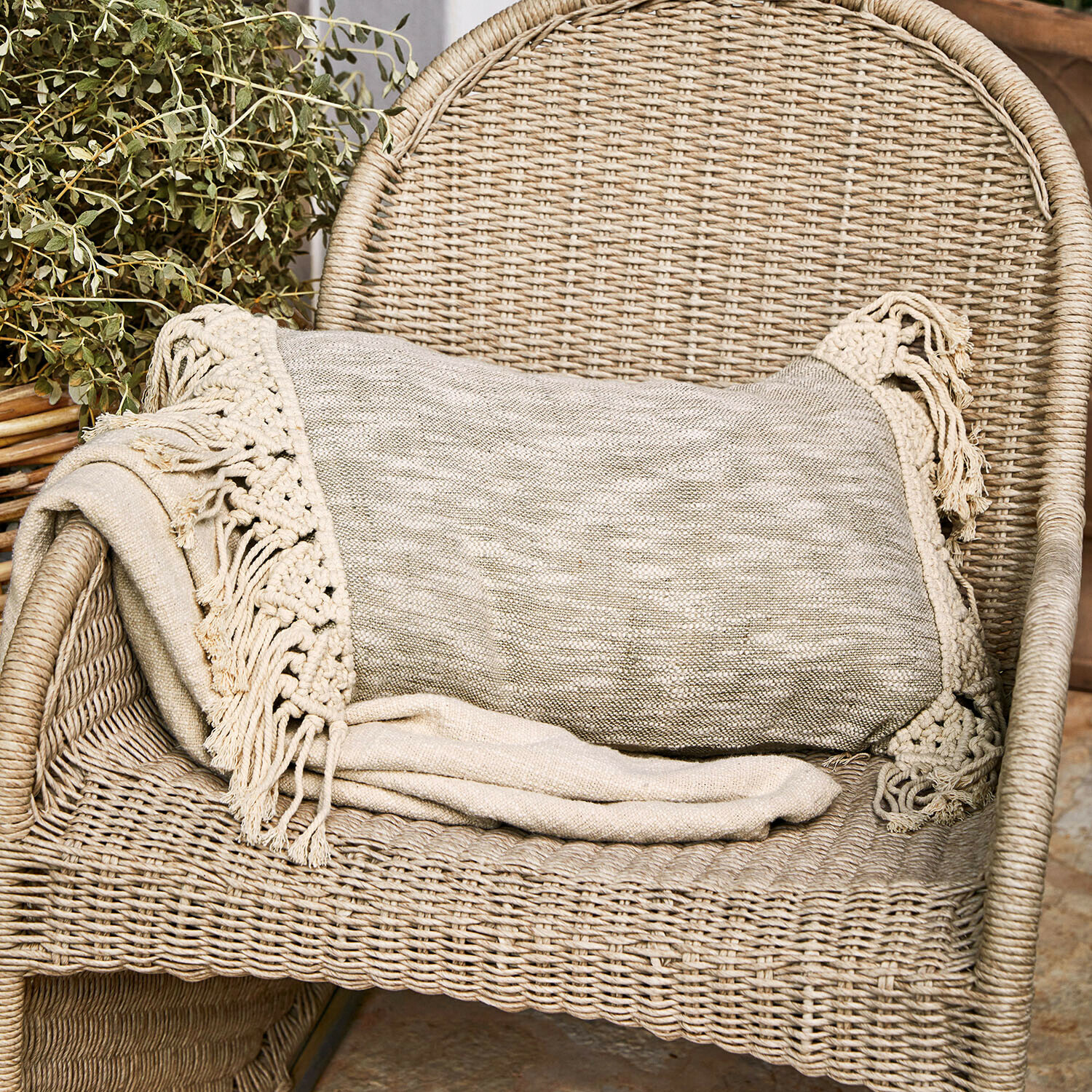 Coperta beige con frange su sedia in vimini, decorazione accogliente per la casa