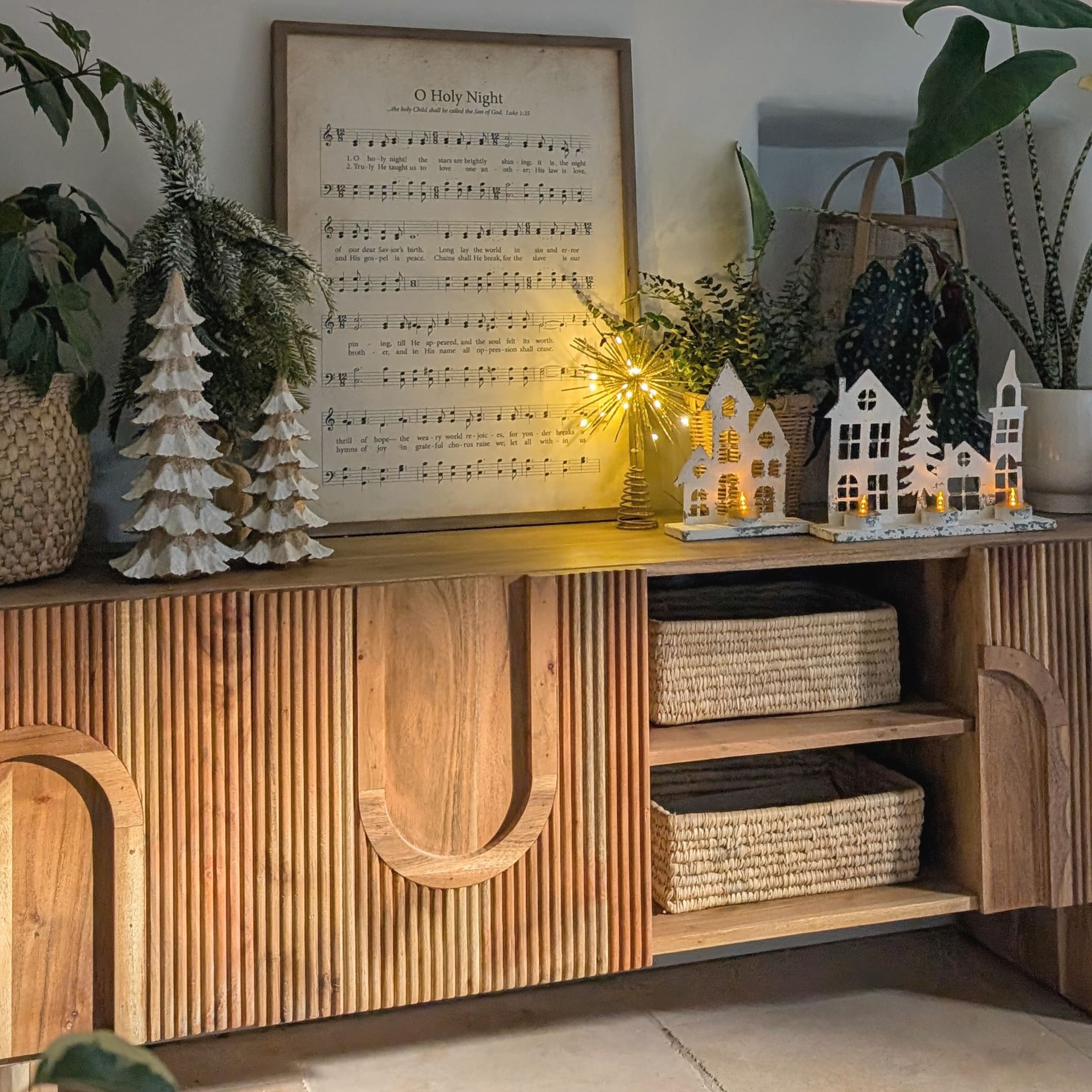 Madia in legno con decorazioni natalizie bianche, casette e alberi illuminati da luci LED calde