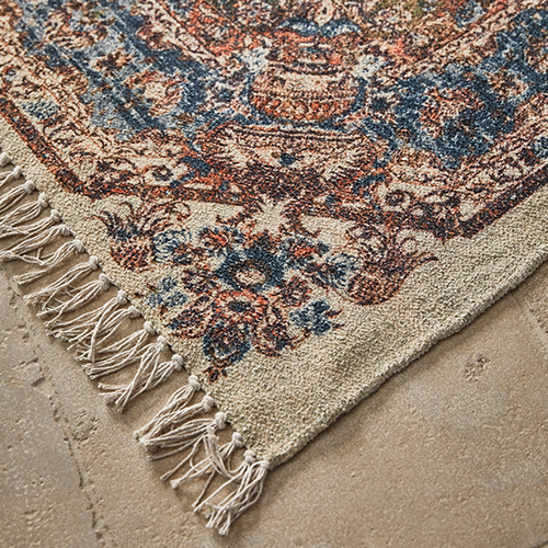Tappeto con frange e motivo orientale beige, blu e rosso su pavimento in pietra