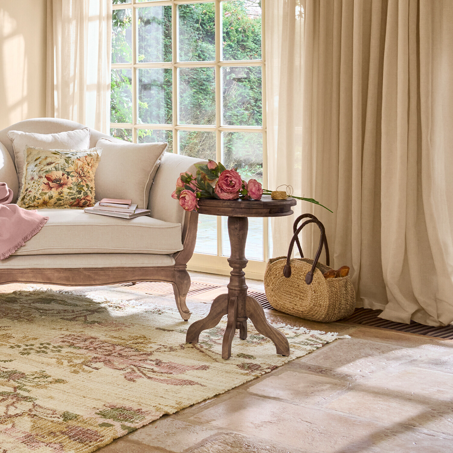 Soggiorno accogliente con divano beige, tavolino in legno e fiori su tappeto a motivo floreale