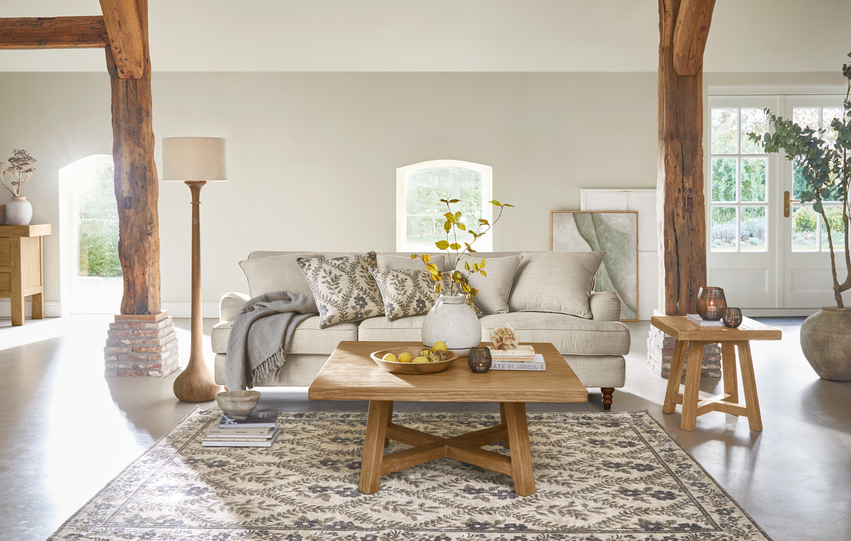 Soggiorno accogliente in stile rustico con divano beige, tavolino in legno e tappeto naturale