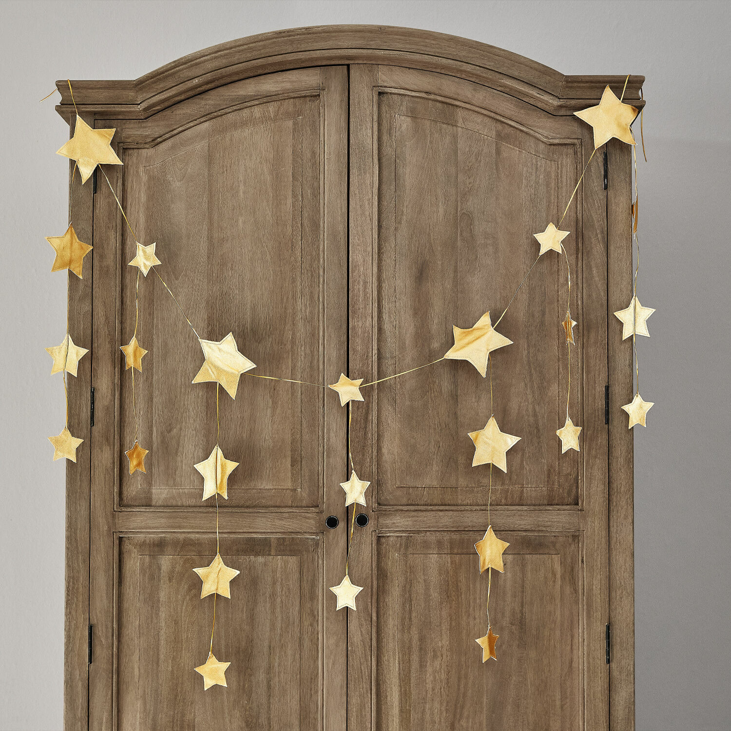 Festone Étoilin Ghirlanda di stelle dorate appesa a un armadio in legno, decorazione natalizia per la casa