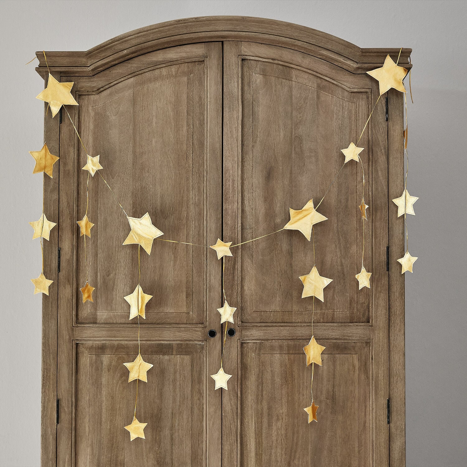 Festone Étoilin Ghirlanda di stelle dorate appesa a un armadio in legno, decorazione natalizia per la casa