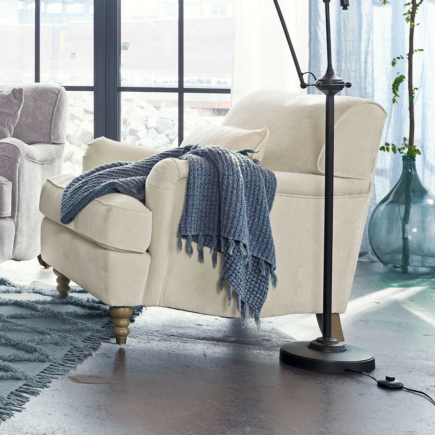 Poltrona beige rivestita con gambe in legno e coperta blu lavorata a maglia in soggiorno moderno