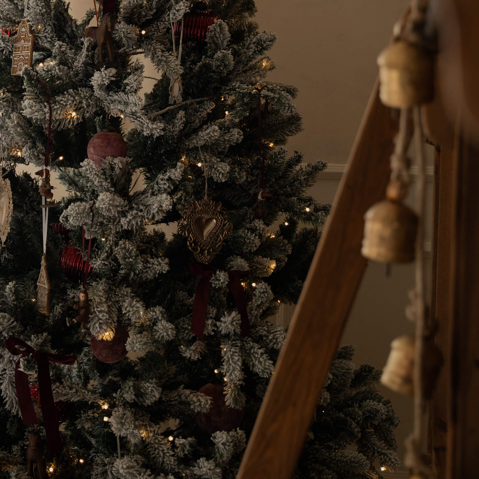 Albero di Natale innevato con decorazioni rosse e dorate e luci calde natalizie
