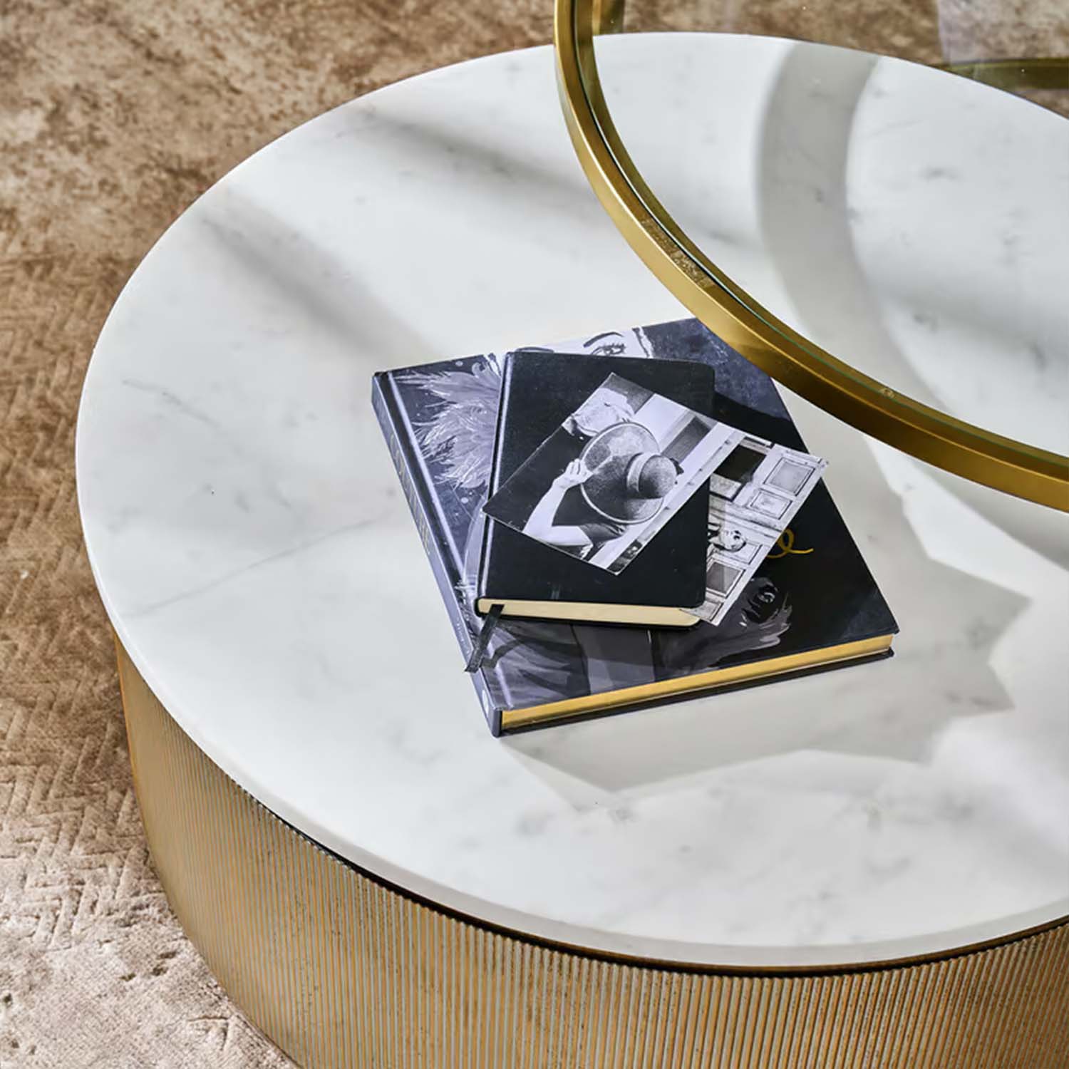 Tavolino rotondo con piano in marmo bianco e base dorata su tappeto beige