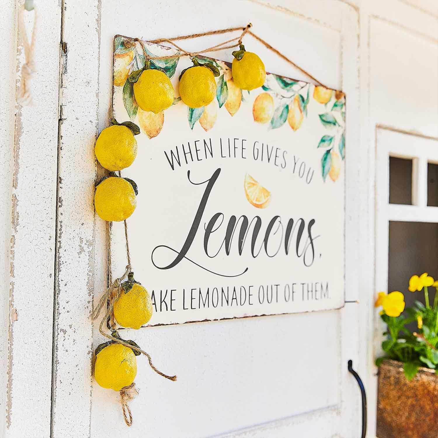 Cartello decorativo con motivo limoni e ghirlanda di limoni gialli appesa a porta bianca