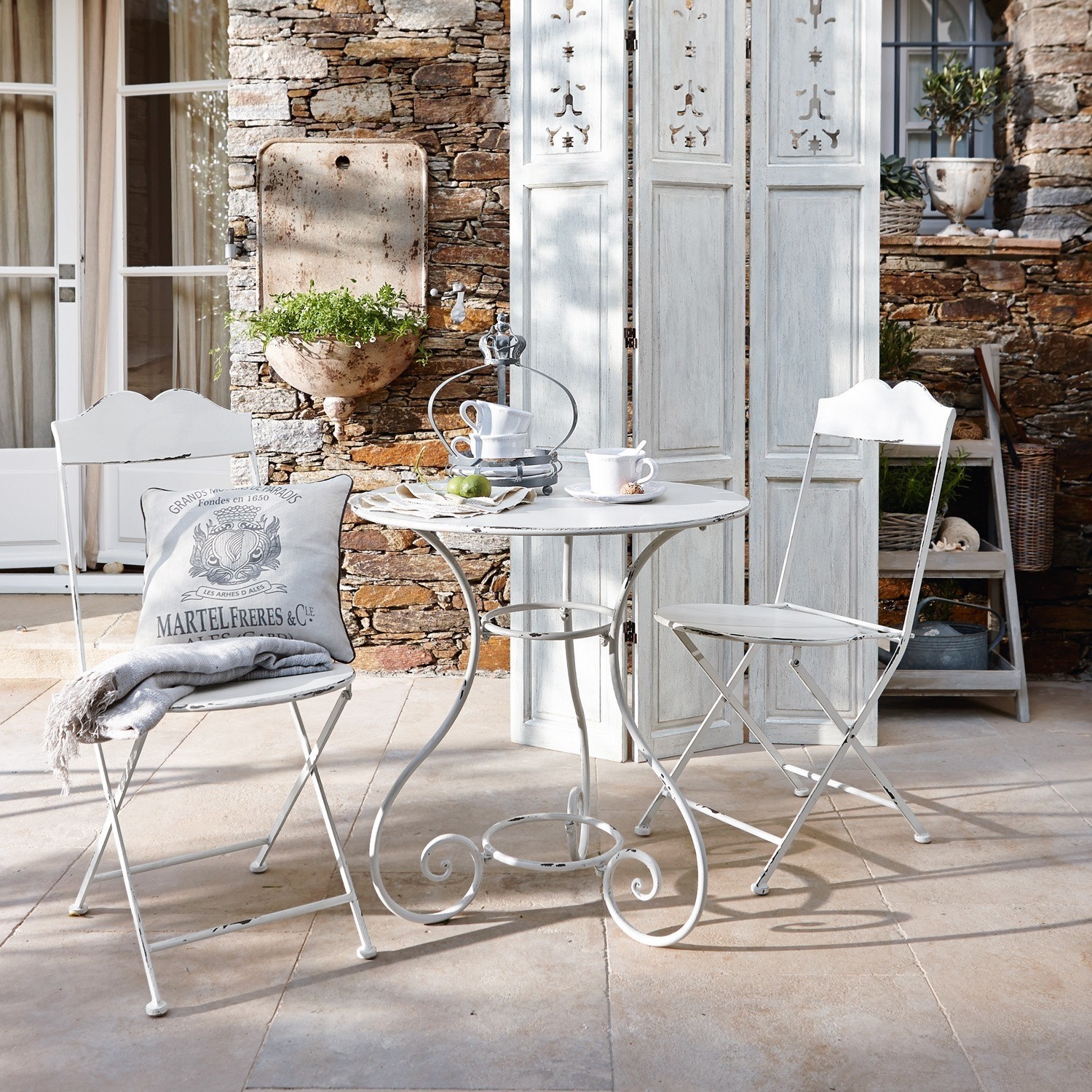 Set tavolino e sedie Iteuil Tavolo rotondo bianco in metallo con due sedie pieghevoli stile vintage su terrazza in pietra