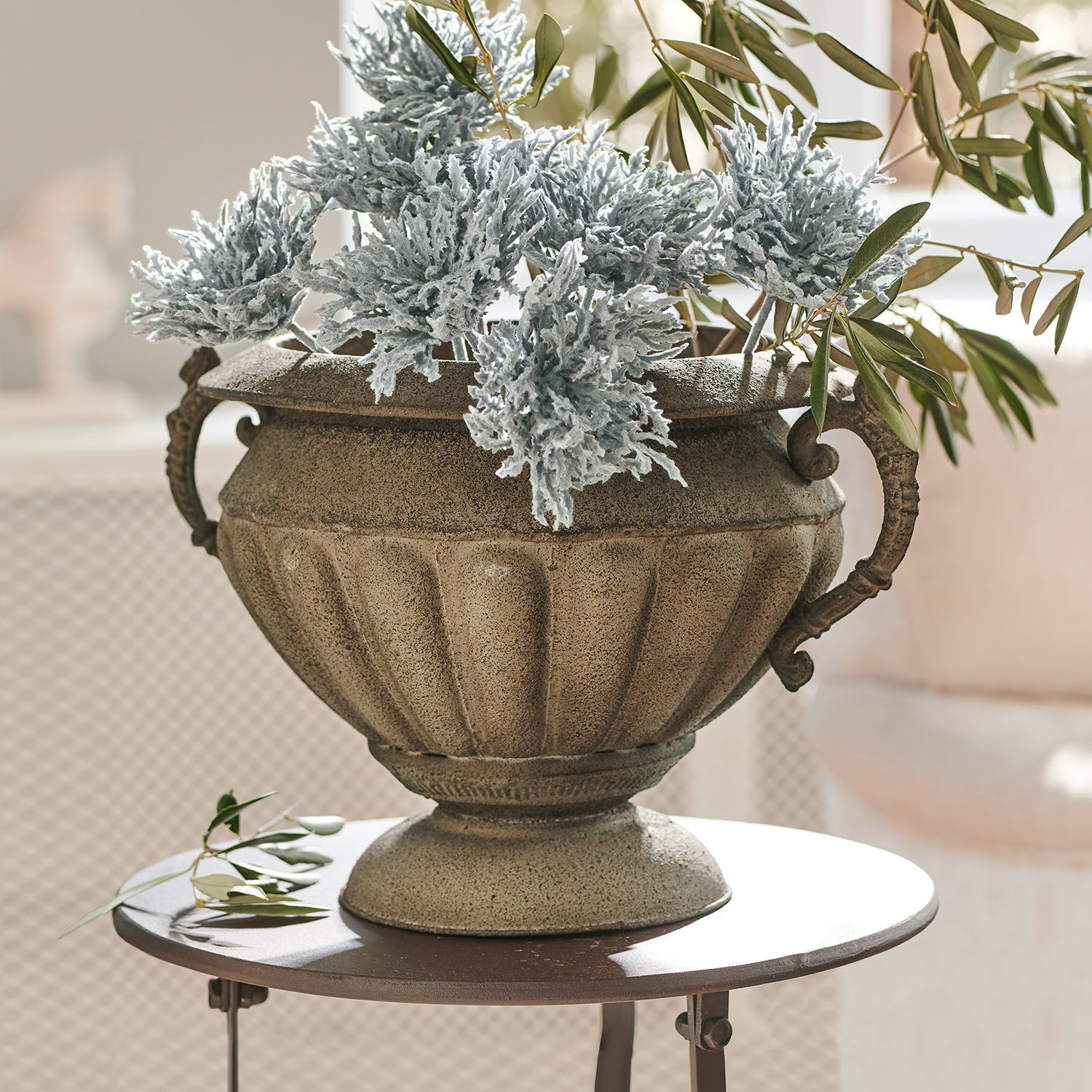 Anfora Acheville Vaso decorativo in pietra beige con foglie verdi e grigie su tavolo rotondo