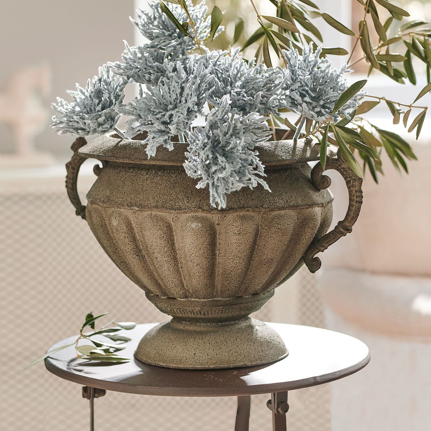 Anfora Acheville Vaso decorativo in pietra beige con foglie verdi e grigie su tavolo rotondo