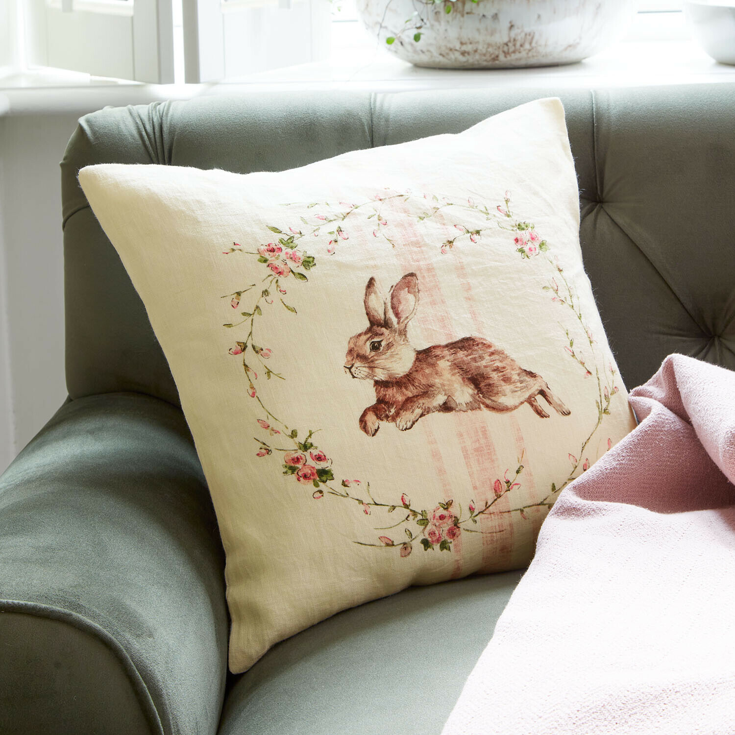 Copricuscino Ravencrest Cuscino in lino beige con stampa coniglio e fiori rosa su divano verde con coperta rosa