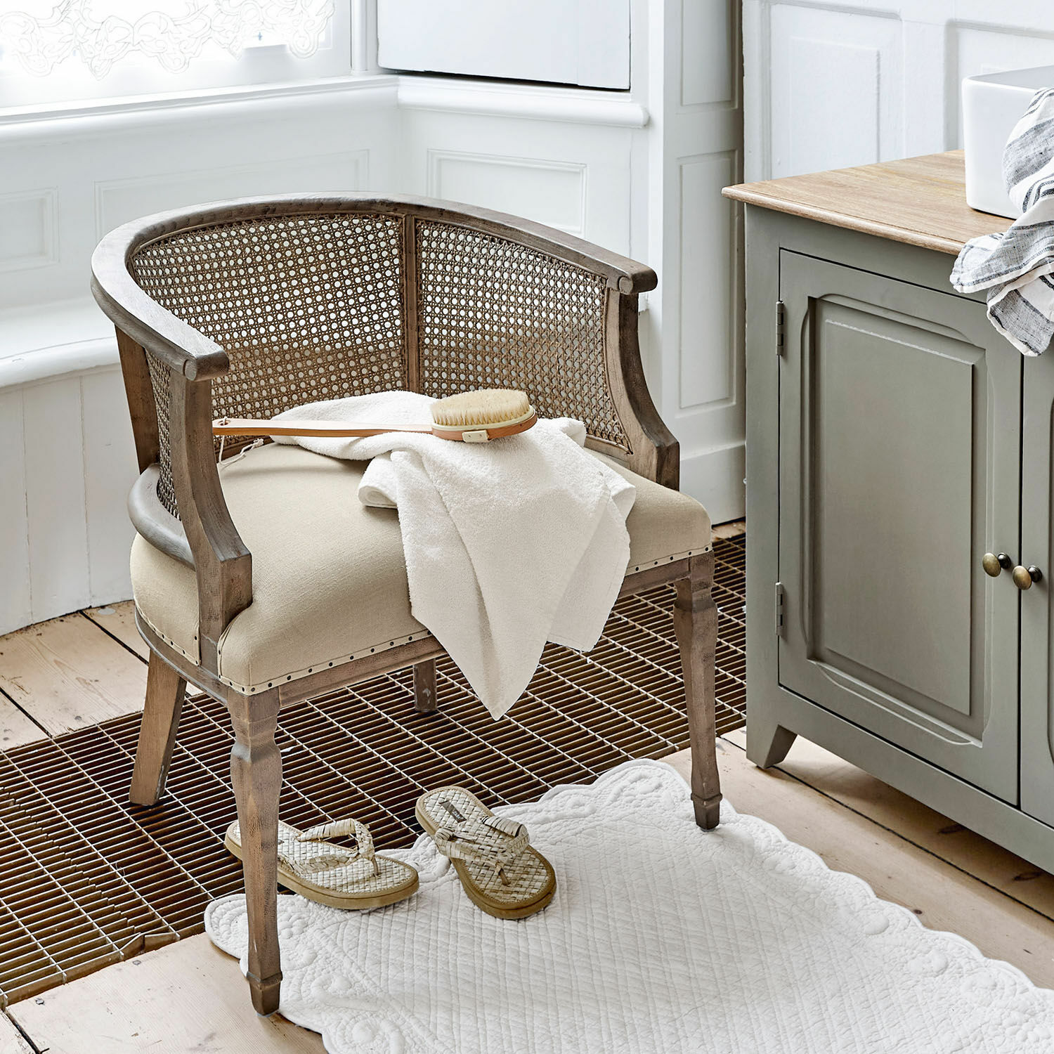 Sedia Curbigny Sedia in legno e rattan beige con seduta imbottita e asciugamano bianco in bagno luminoso
