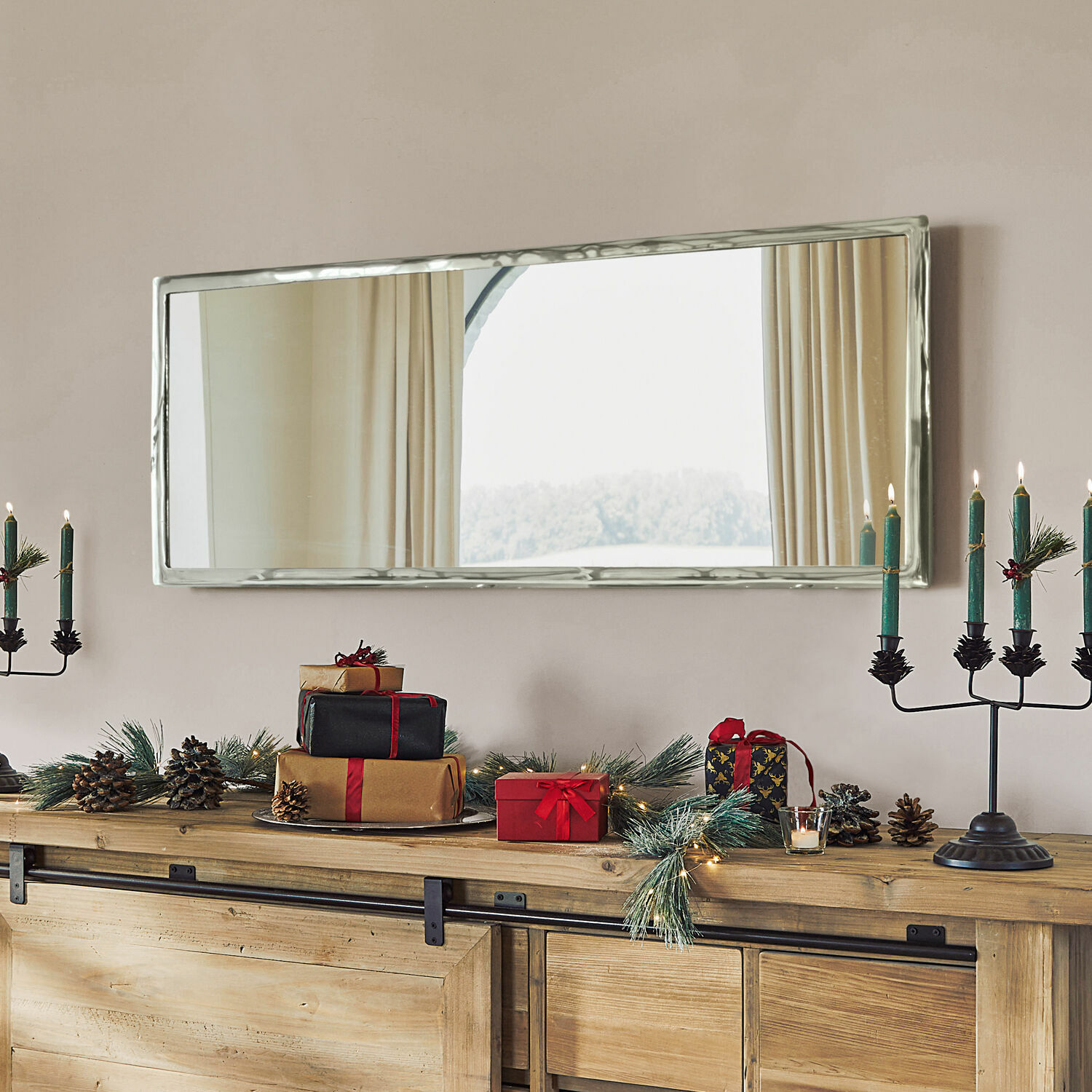 Specchio Kaplin Specchio rettangolare con cornice metallica argento sopra credenza in legno con decorazioni natalizie