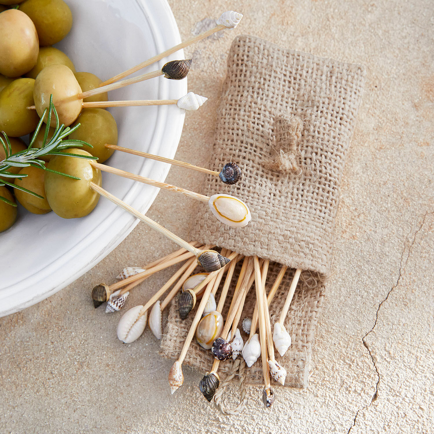 Bastoncini decorativi Bijou Set di stuzzicadenti con conchiglie naturali in sacchetto di lino vicino a olive verdi