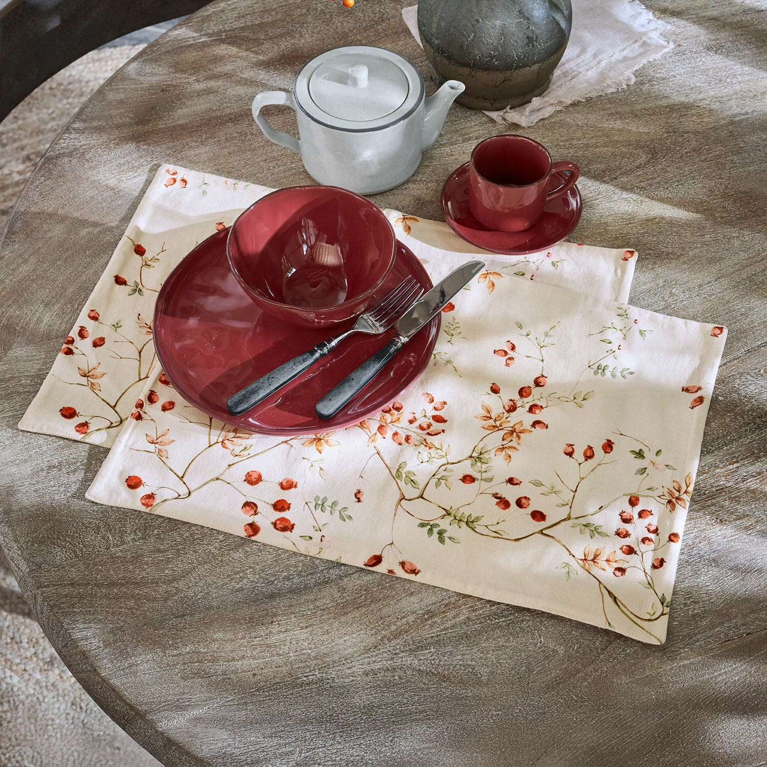 Due coppie di tovagliette Mauriac Servizio in ceramica rossa su tovaglietta di lino con motivo frutti su tavolo in legno