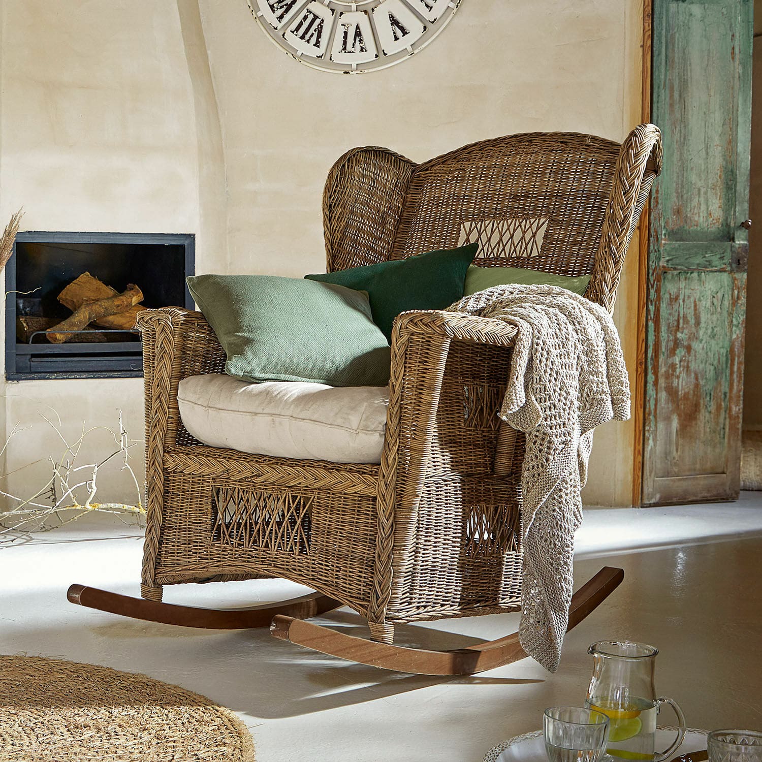 Sedia a dondolo Jeveren Sedia a dondolo in rattan naturale con cuscini verdi e coperta in ambiente accogliente