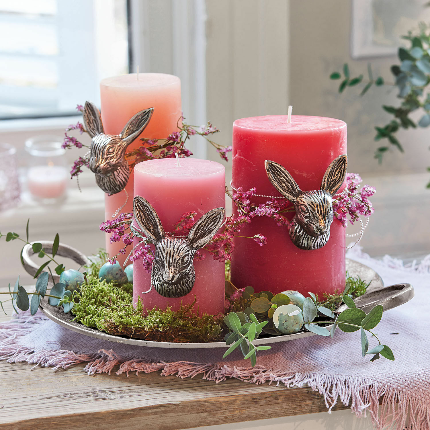 Set di 3 candele Pretin Set di tre candele rosa con decorazioni a testa di coniglio e muschio verde su vassoio in metallo