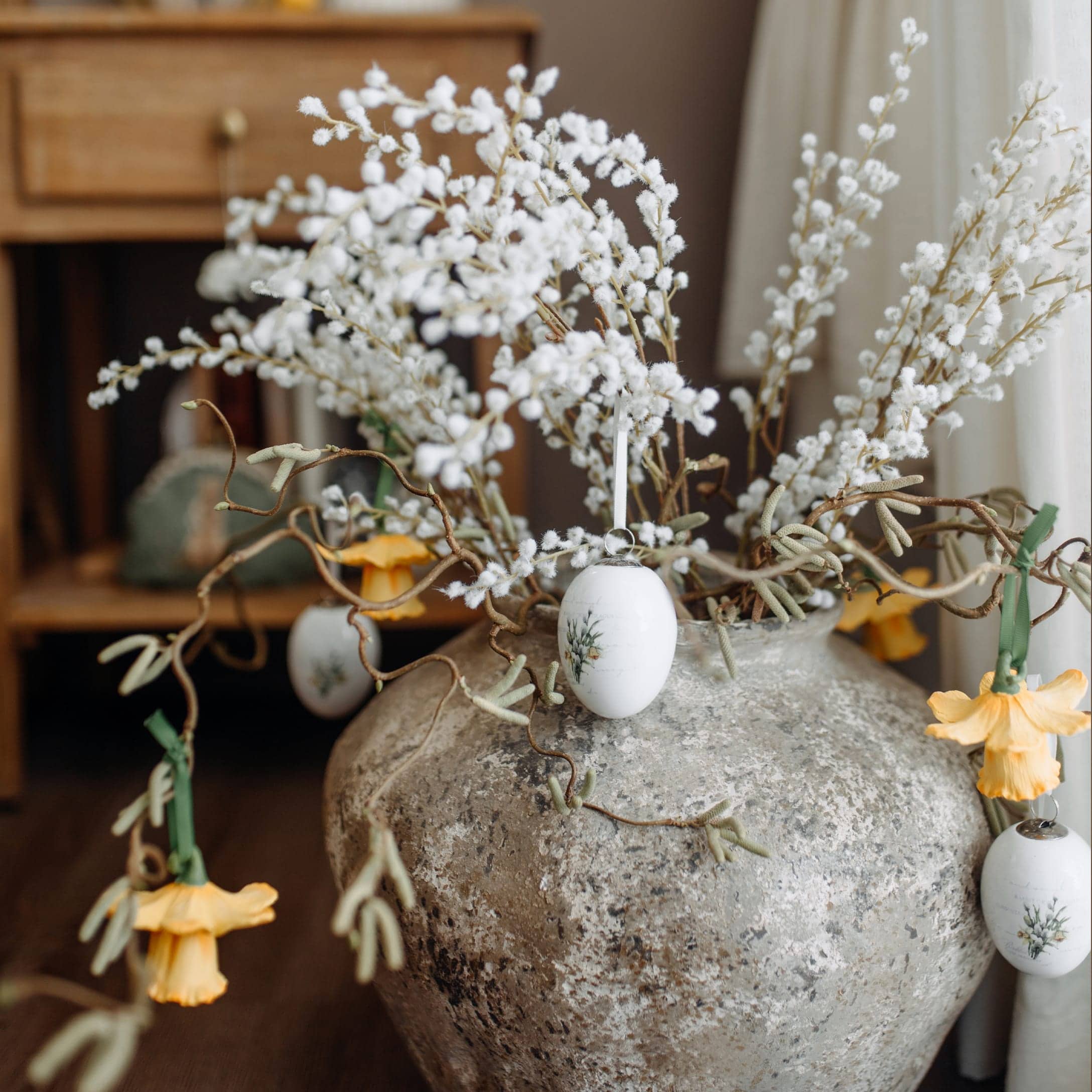 Vaso in ceramica grigia con rami bianchi e fiori gialli per decorazione primaverile d'interni
