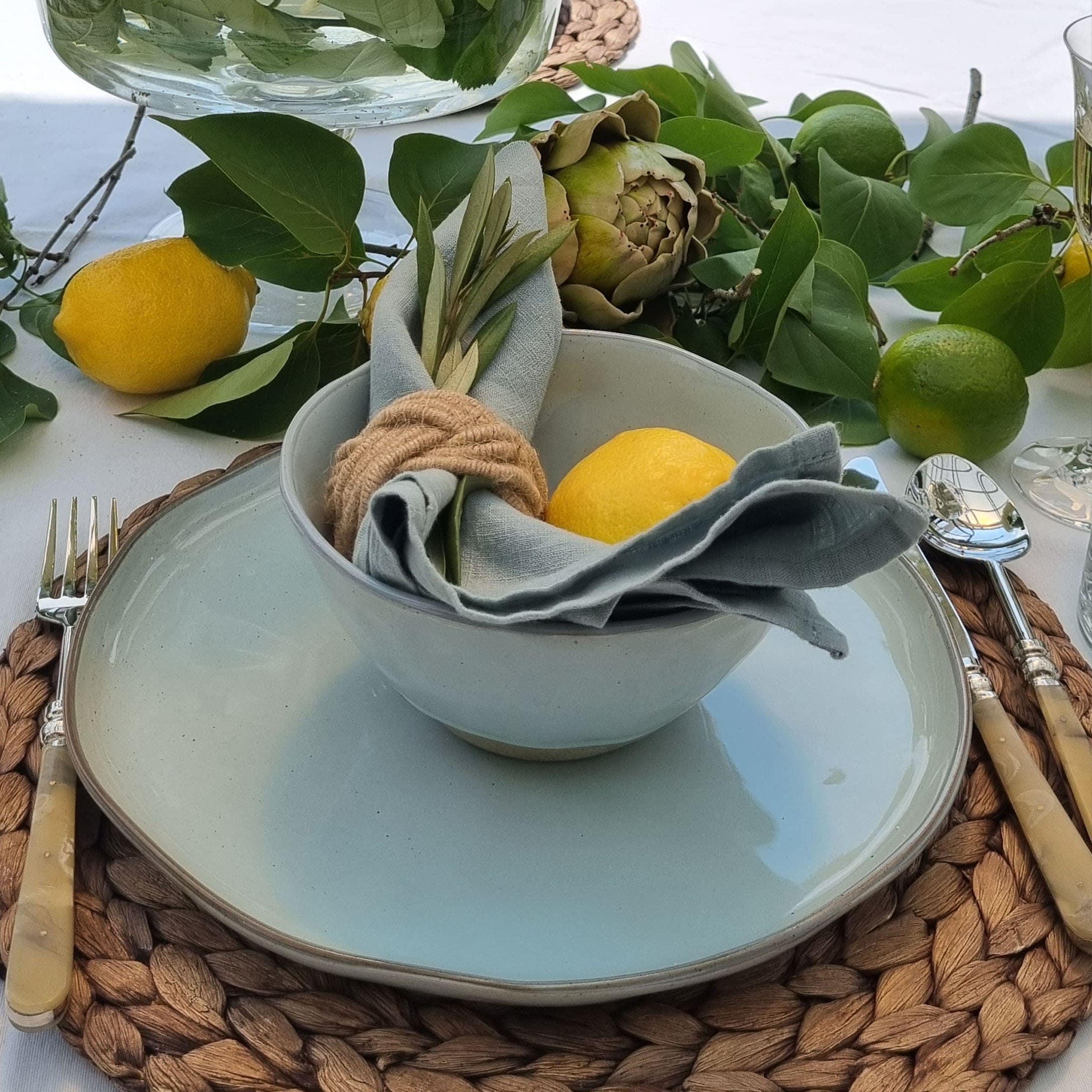 Set da tavola con ciotola e piatto in ceramica chiara su sottopentola intrecciato con decorazione al limone