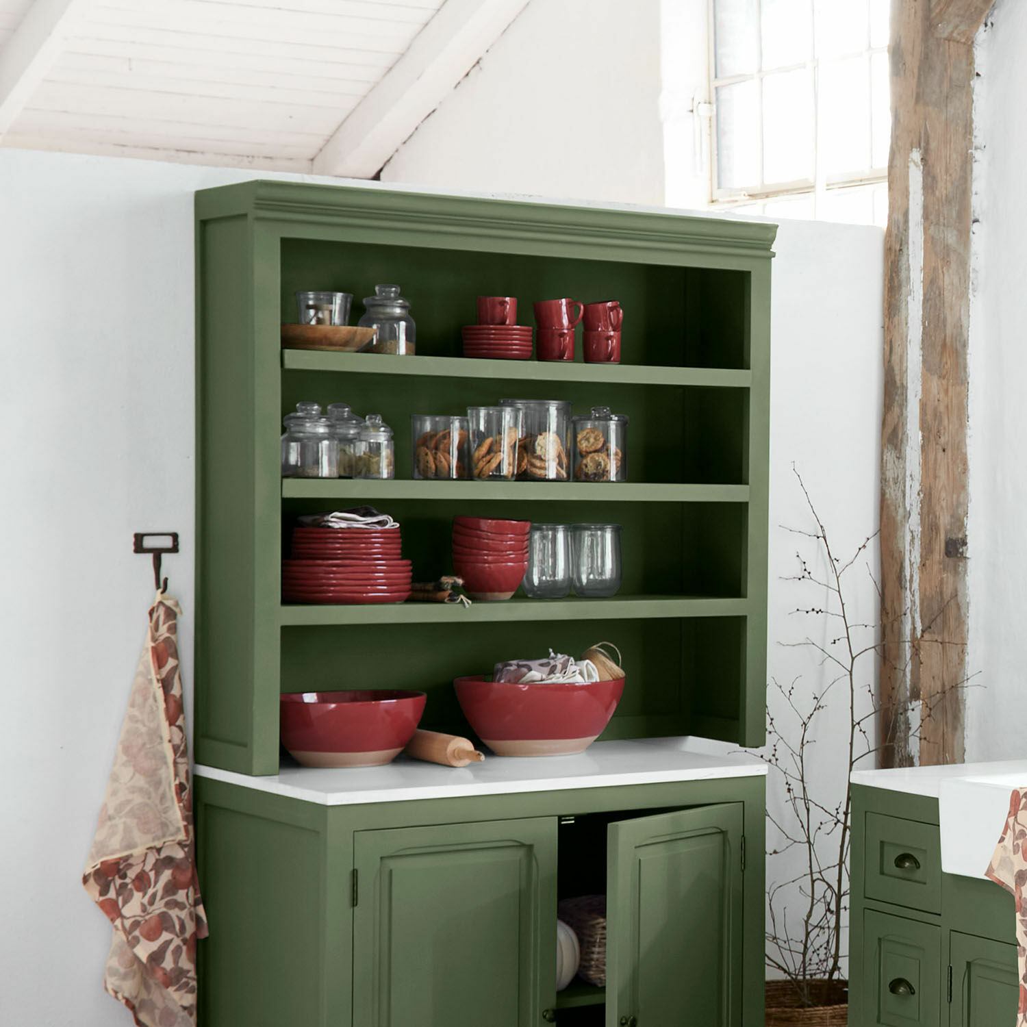 Vetrina da cucina Lansbury Credenza verde in legno con ciotole rosse in ceramica e barattoli di vetro con biscotti in cucina rustica