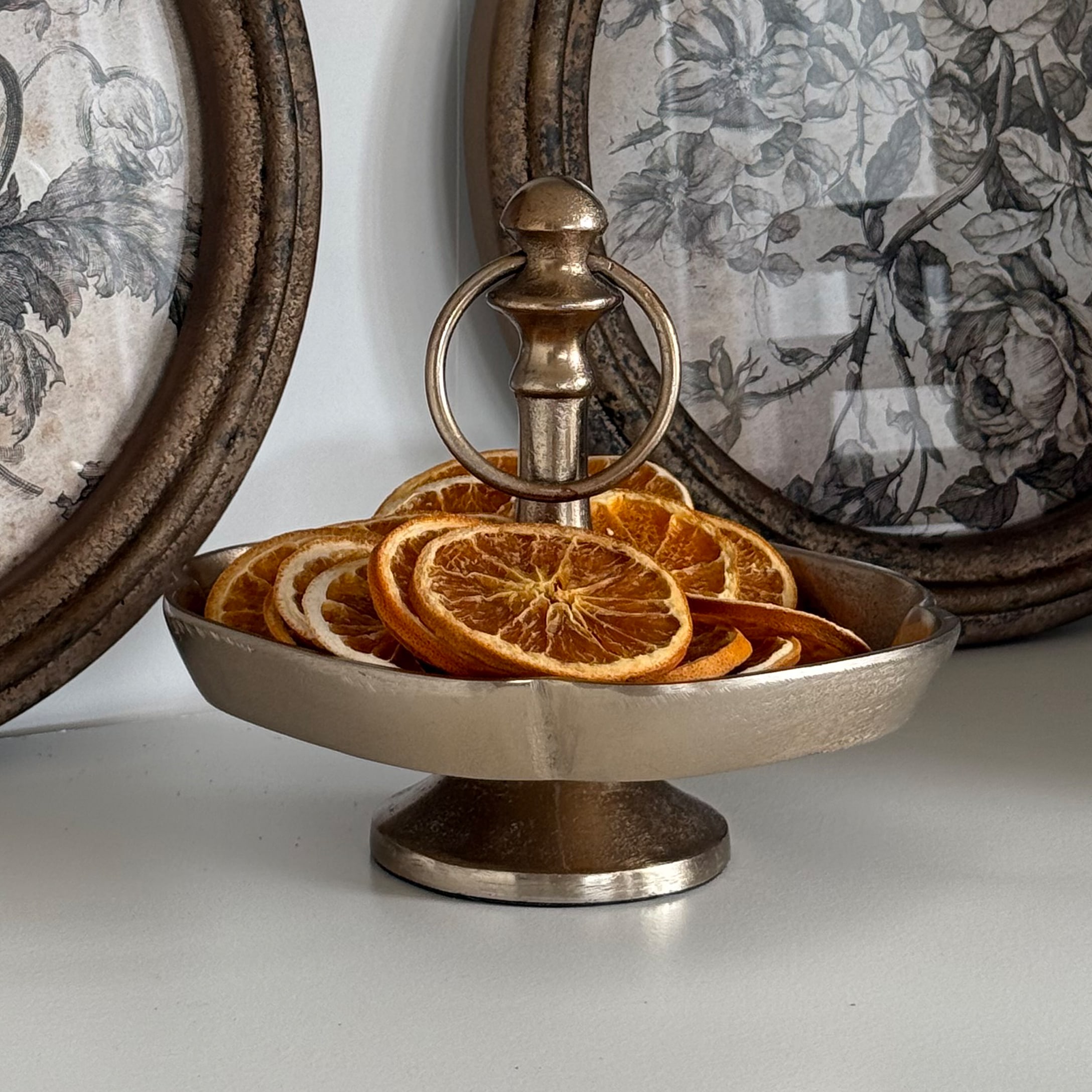 Vassoio metallico argentato con manico contenente fette di arancia essiccate per decorazione autunnale