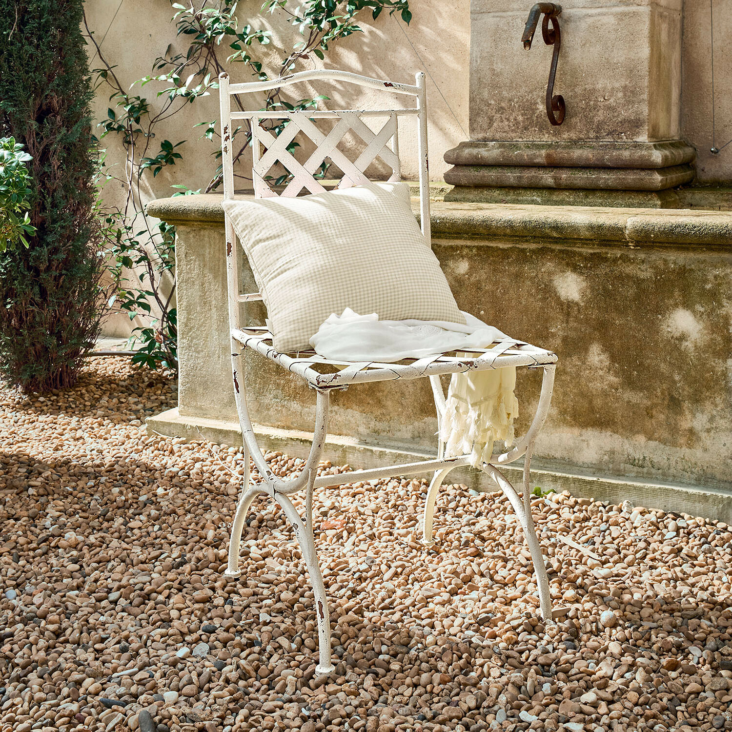 Sedia Gavrielle Sedia da giardino in metallo bianco con cuscino a quadri e sciarpa leggera su ghiaia