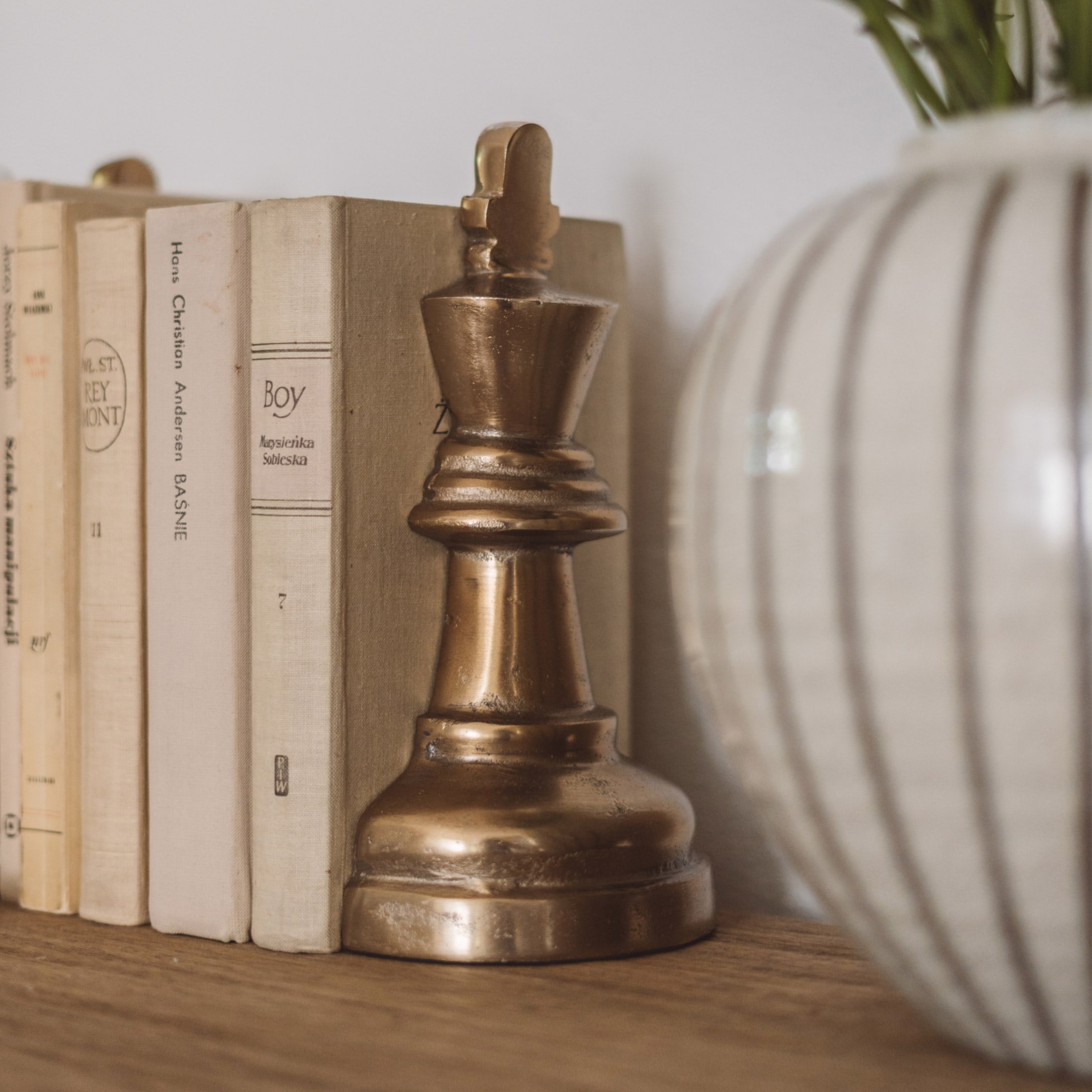 Figura decorativa del re degli scacchi in ottone su mensola con libri e vaso