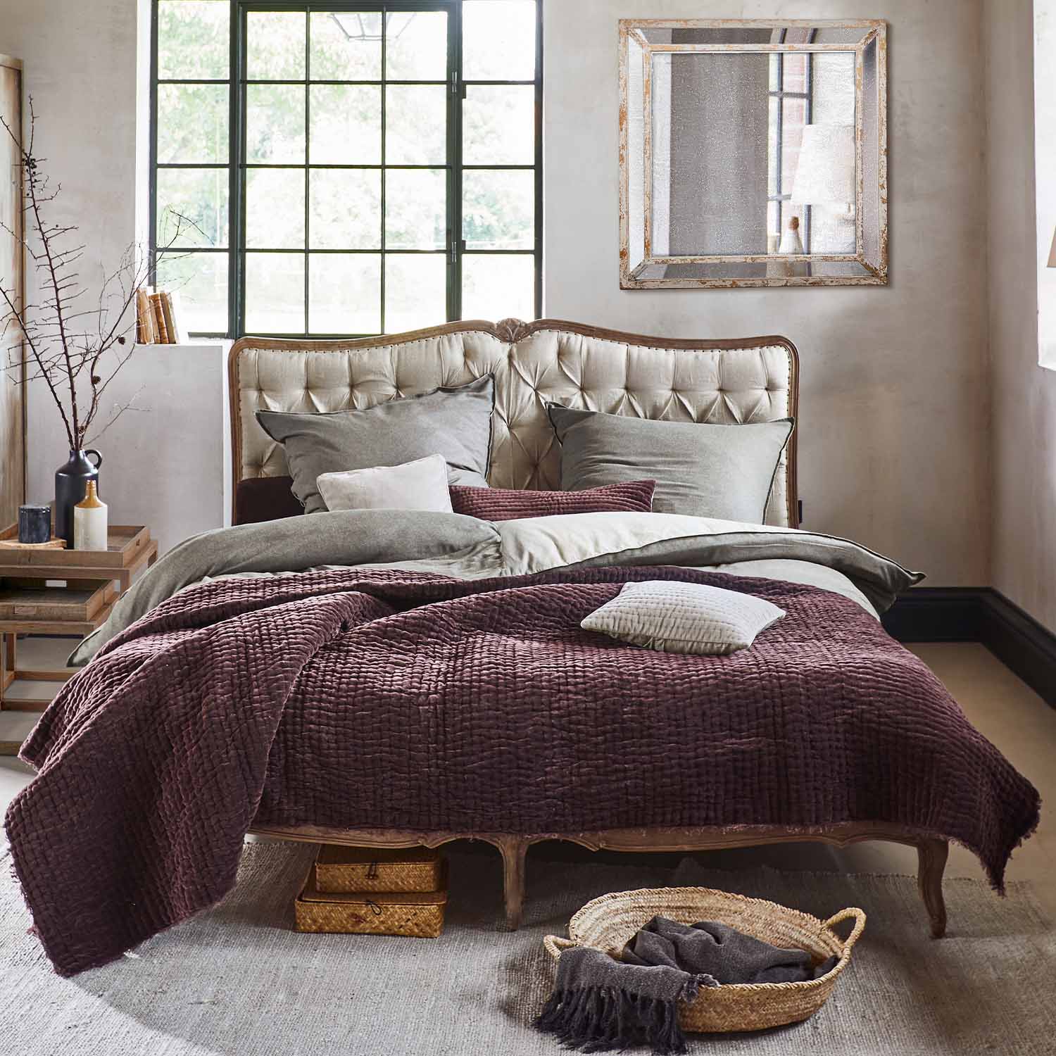 Letto con testiera imbottita beige e coperta bordeaux in tessuto morbido stile vintage