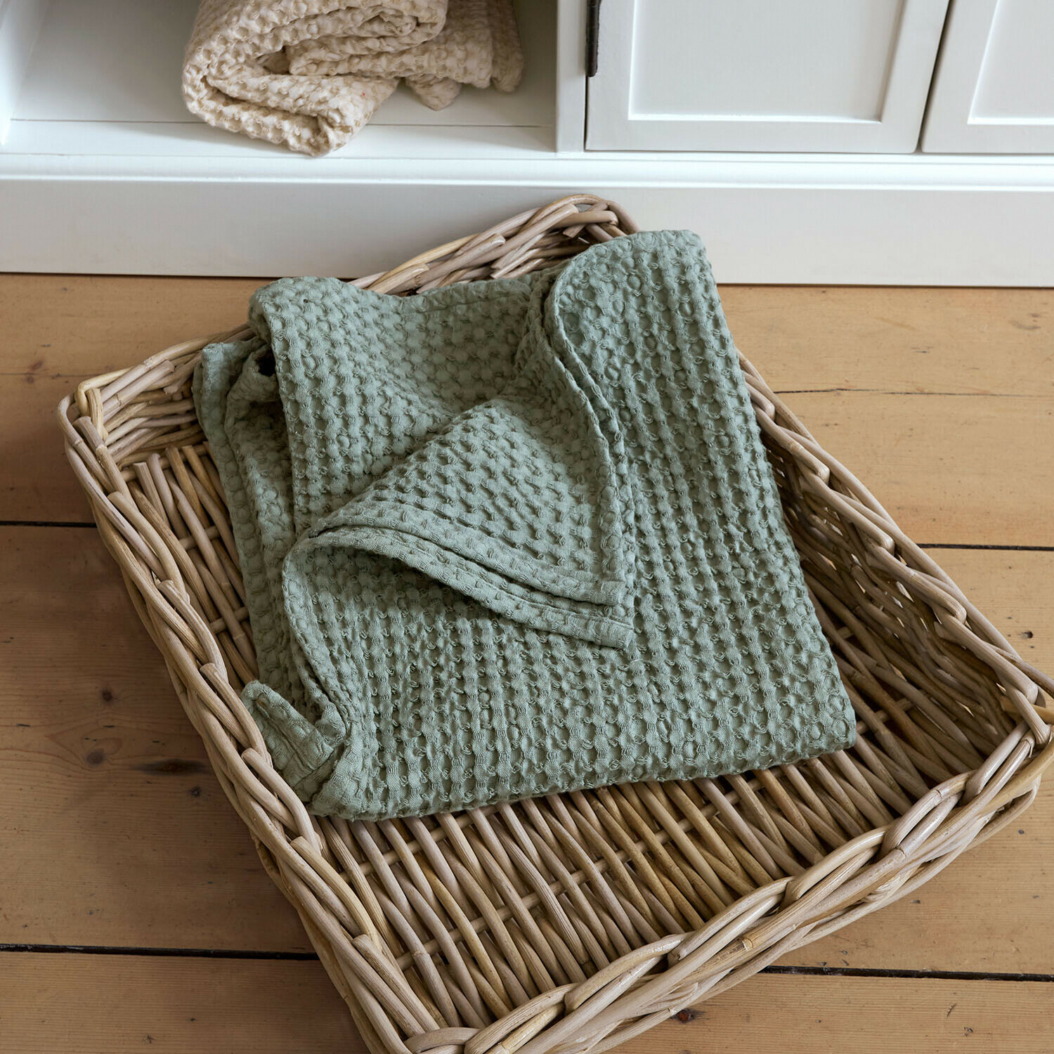 Asciugamano Maralei Coperta verde in cotone a nido d'ape in cesto di vimini su pavimento in legno