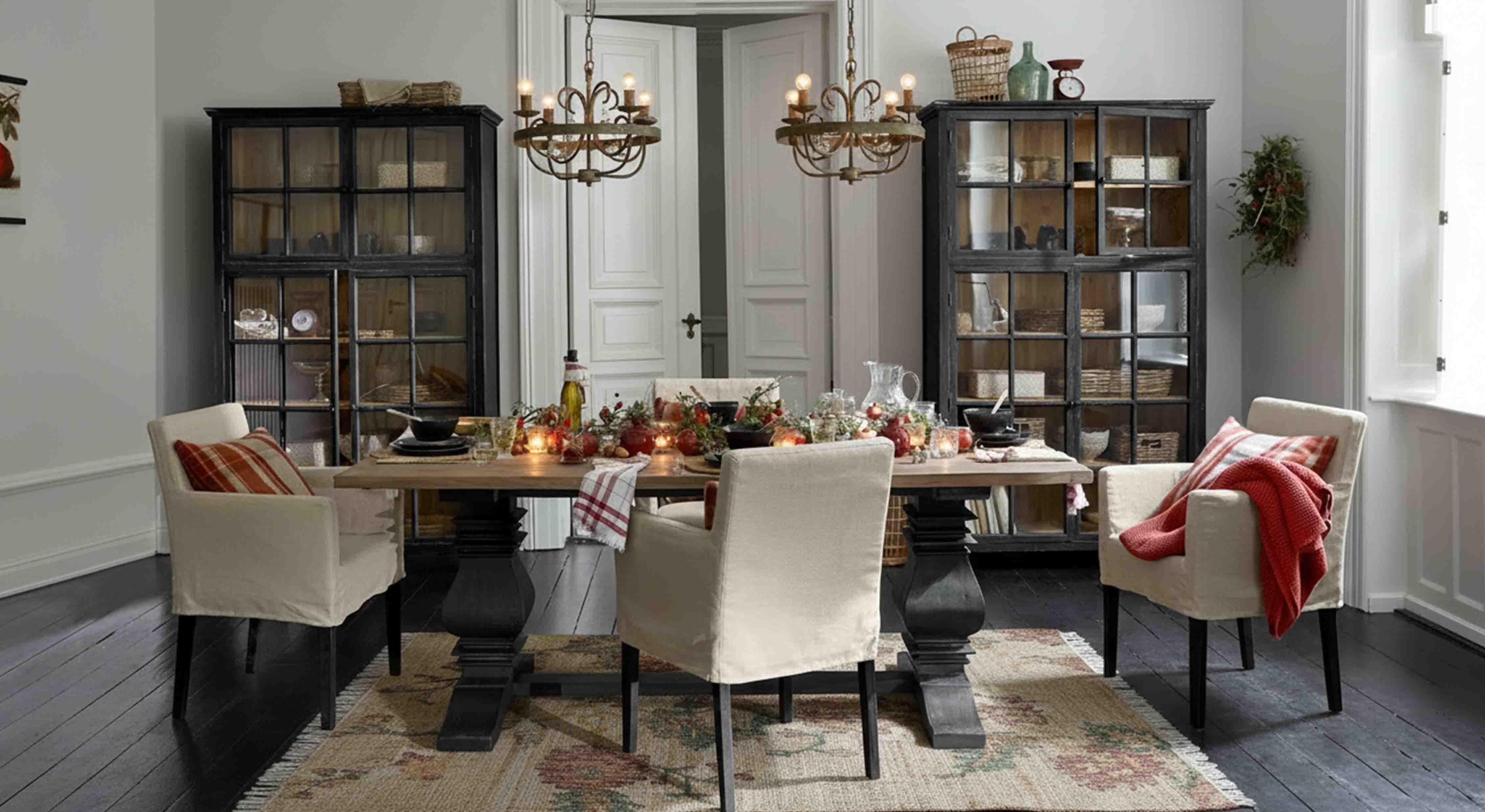 Sala da pranzo con tavolo in legno e sedie crema, decorazioni rustiche e lampadari sospesi
