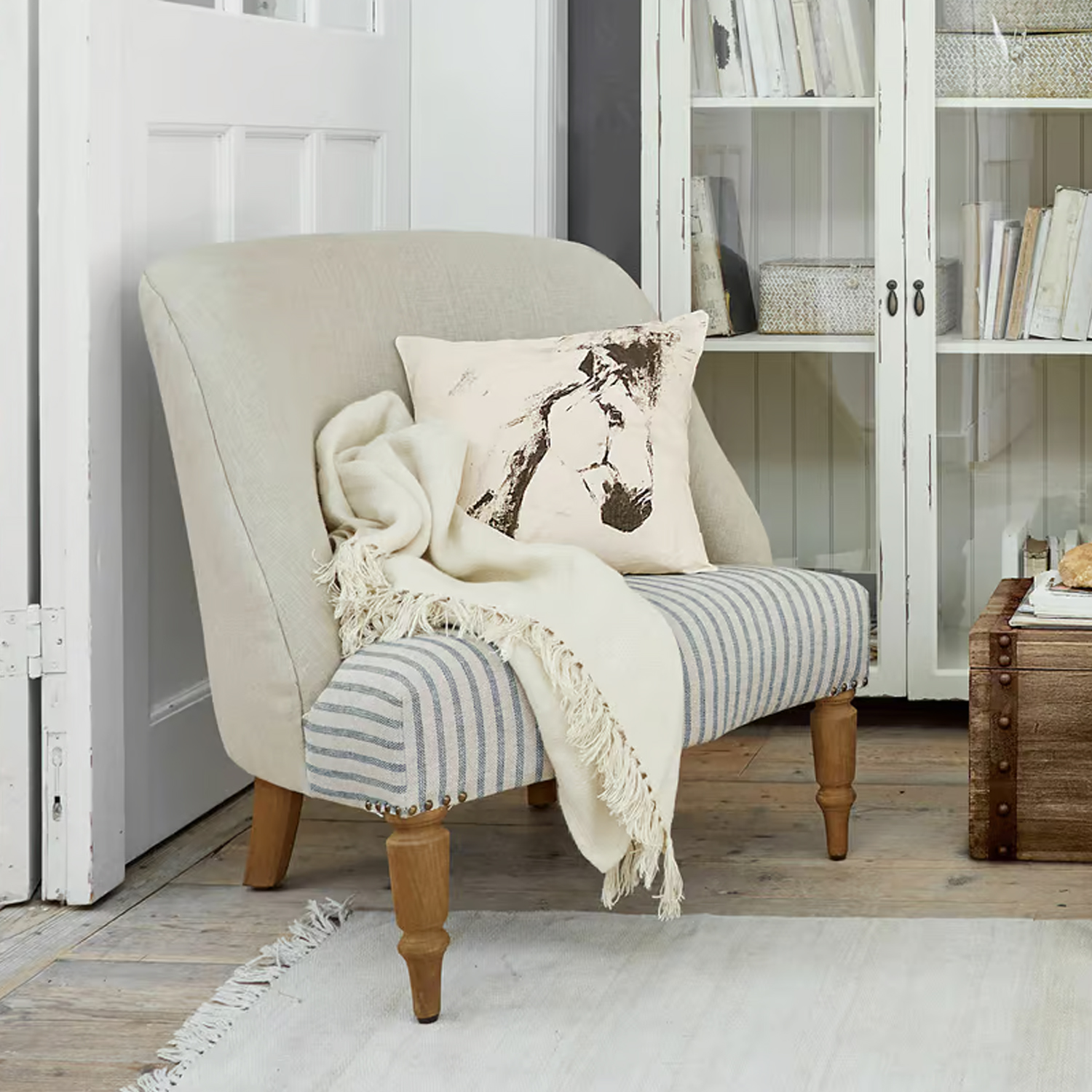 Divano bicolore imbottito con gambe in legno, cuscino con stampa cavallo e coperta crema