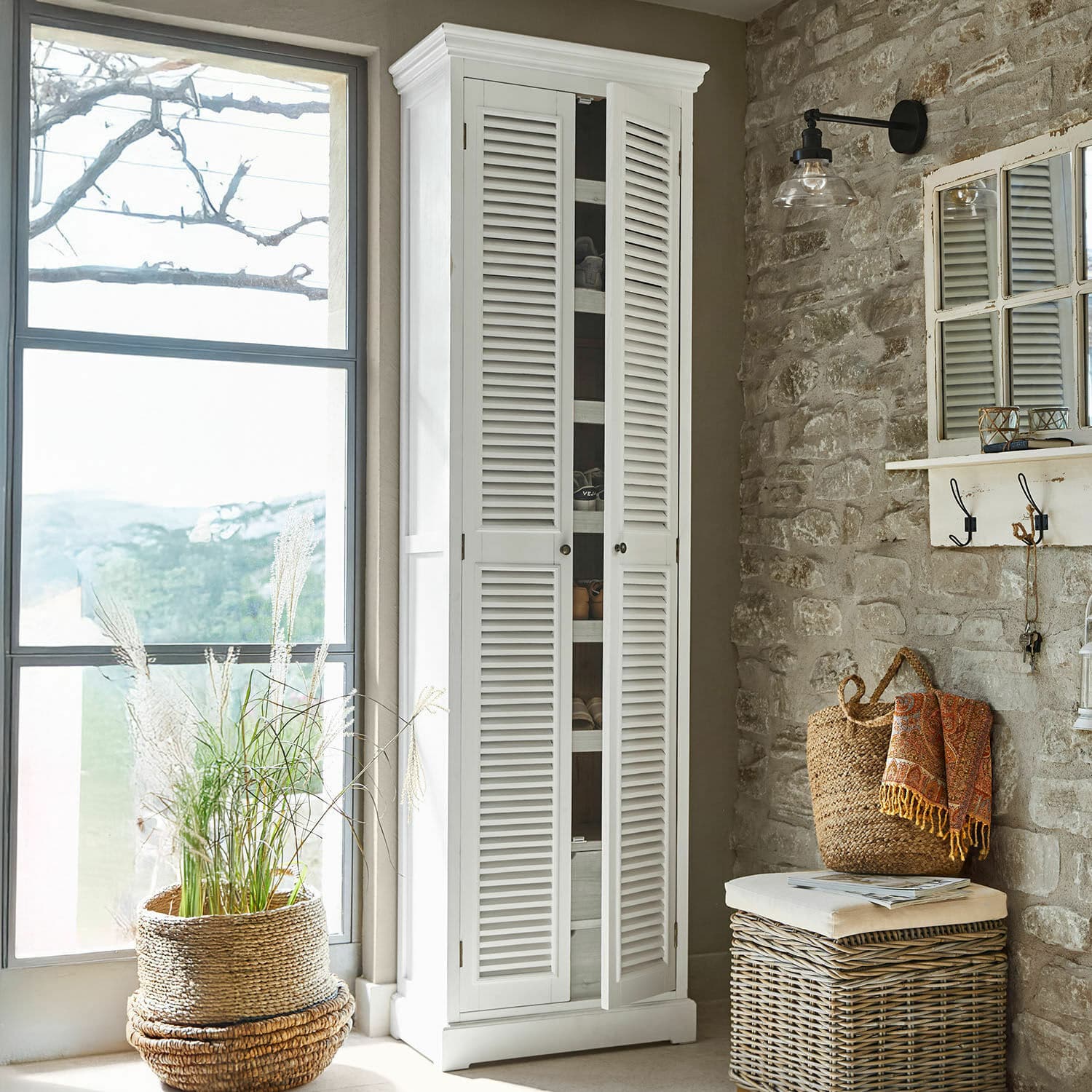 Scarpiera Blossomby Armadio bianco in legno con ante a persiana in interno rustico con parete in pietra