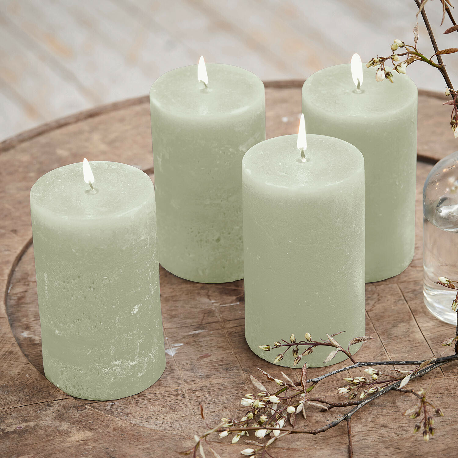 Set di 4 candele Braga Set di quattro candele verdi in cera su tavolo di legno con decorazione floreale