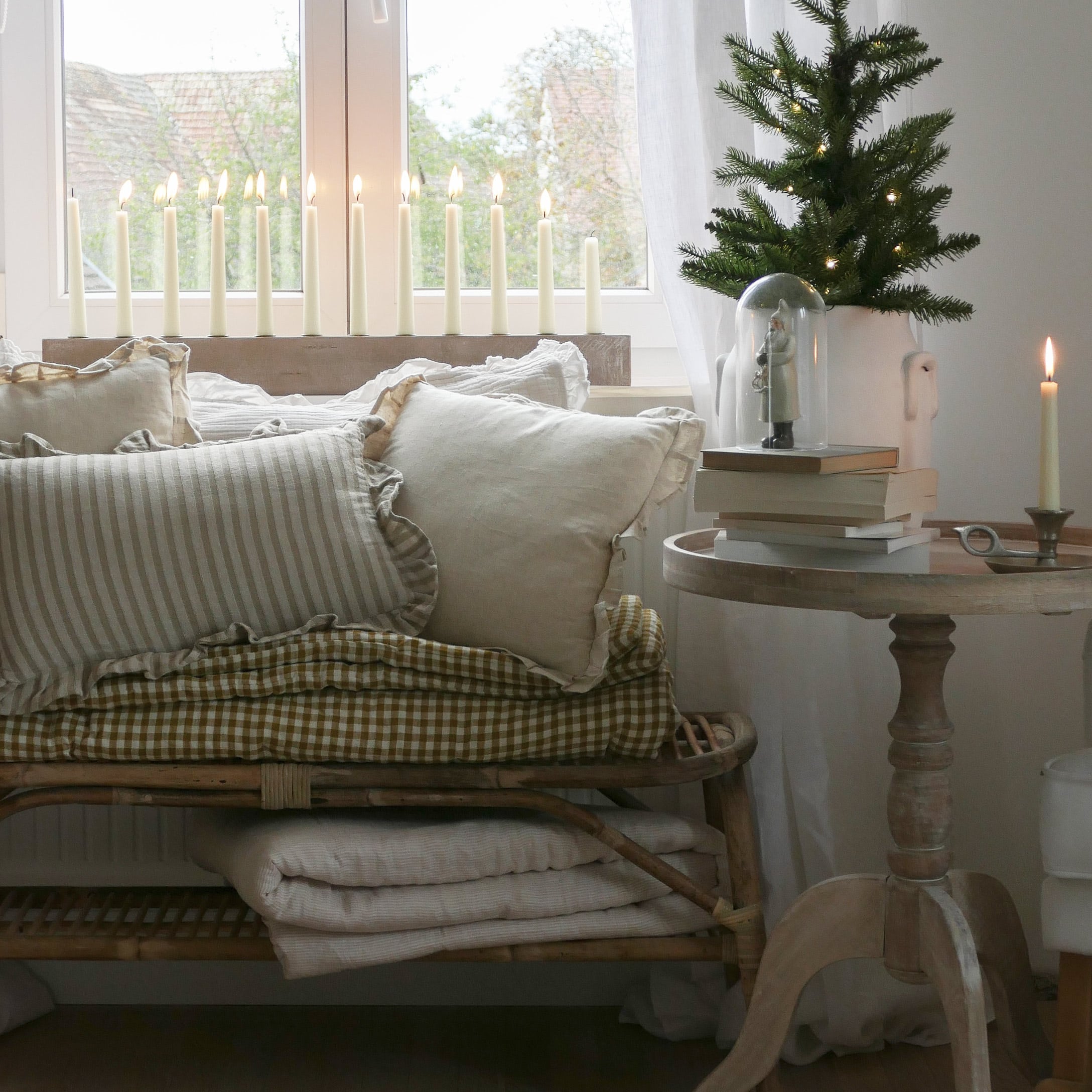 Angolo accogliente con cuscini beige e tavolo in legno con decorazioni e candele accese