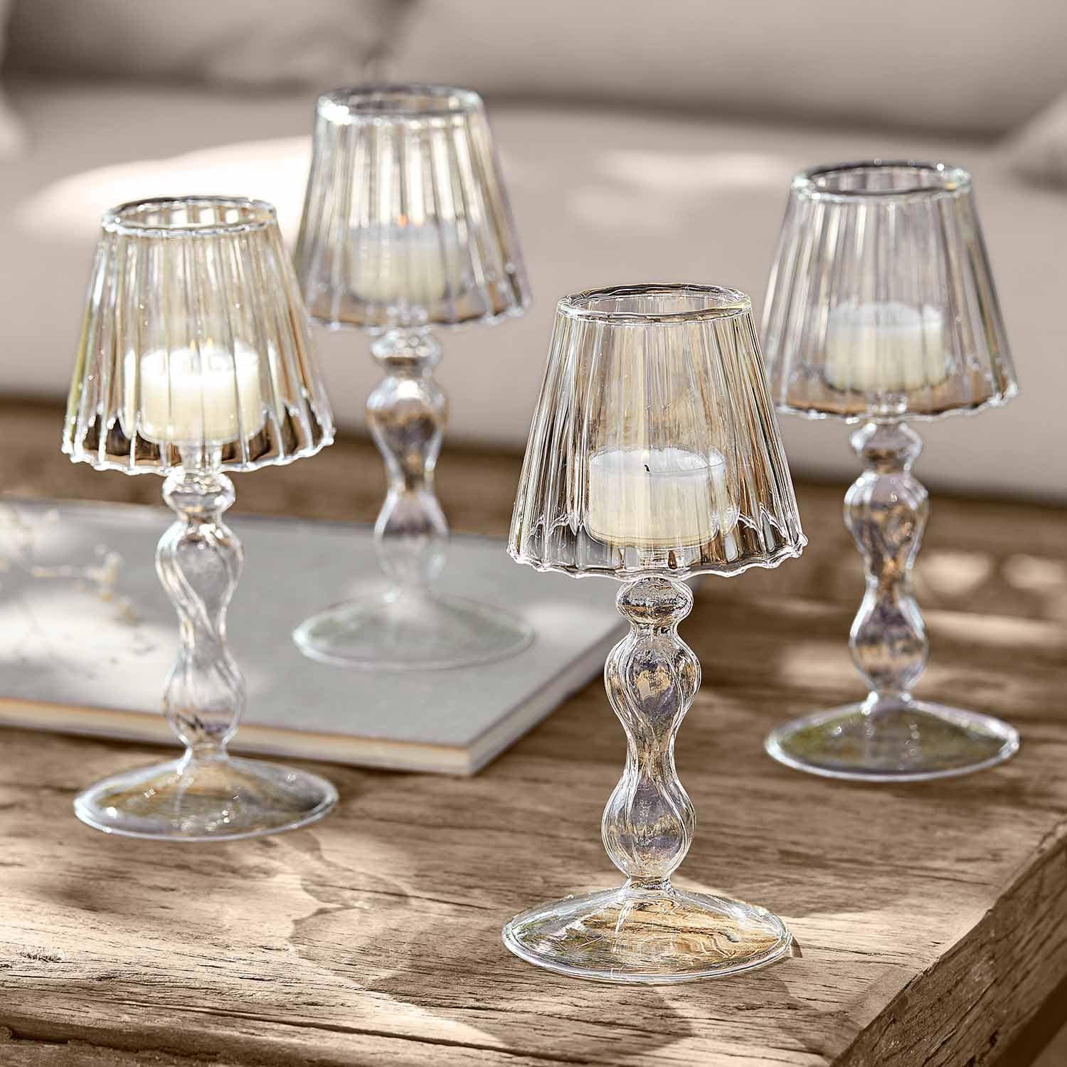 Portacandele in vetro trasparente con candele bianche su tavolo in legno per decorazione