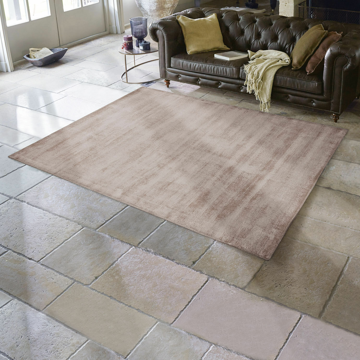 Tappeto Mariselle Tappeto beige in materiale morbido su pavimento in pietra in soggiorno con divano in pelle marrone