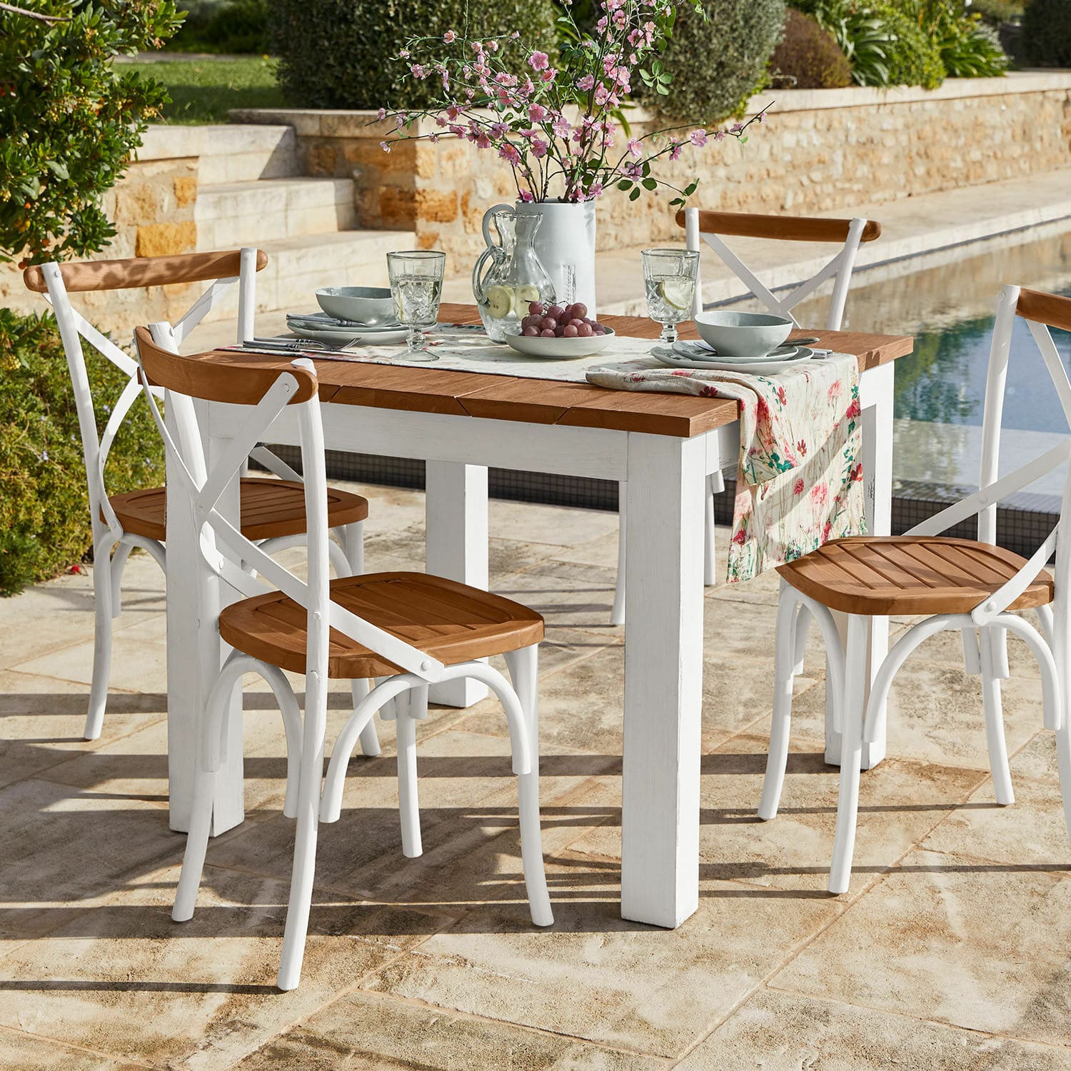 Tavolo Kirkdale Set di mobili da giardino con tavolo bianco in legno e sedie con seduta in legno su terrazza in pietra