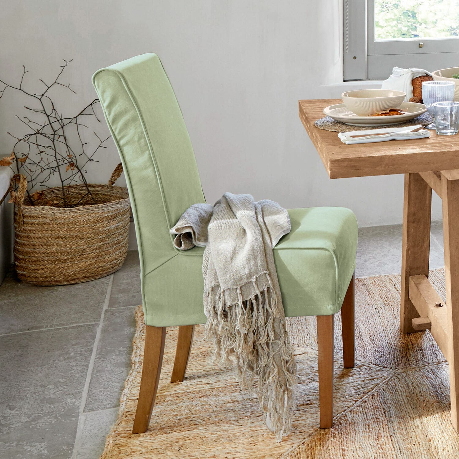 Sedia con coprisedia Mankato Sedia imbottita verde chiaro con gambe in legno e coperta beige in sala da pranzo luminosa