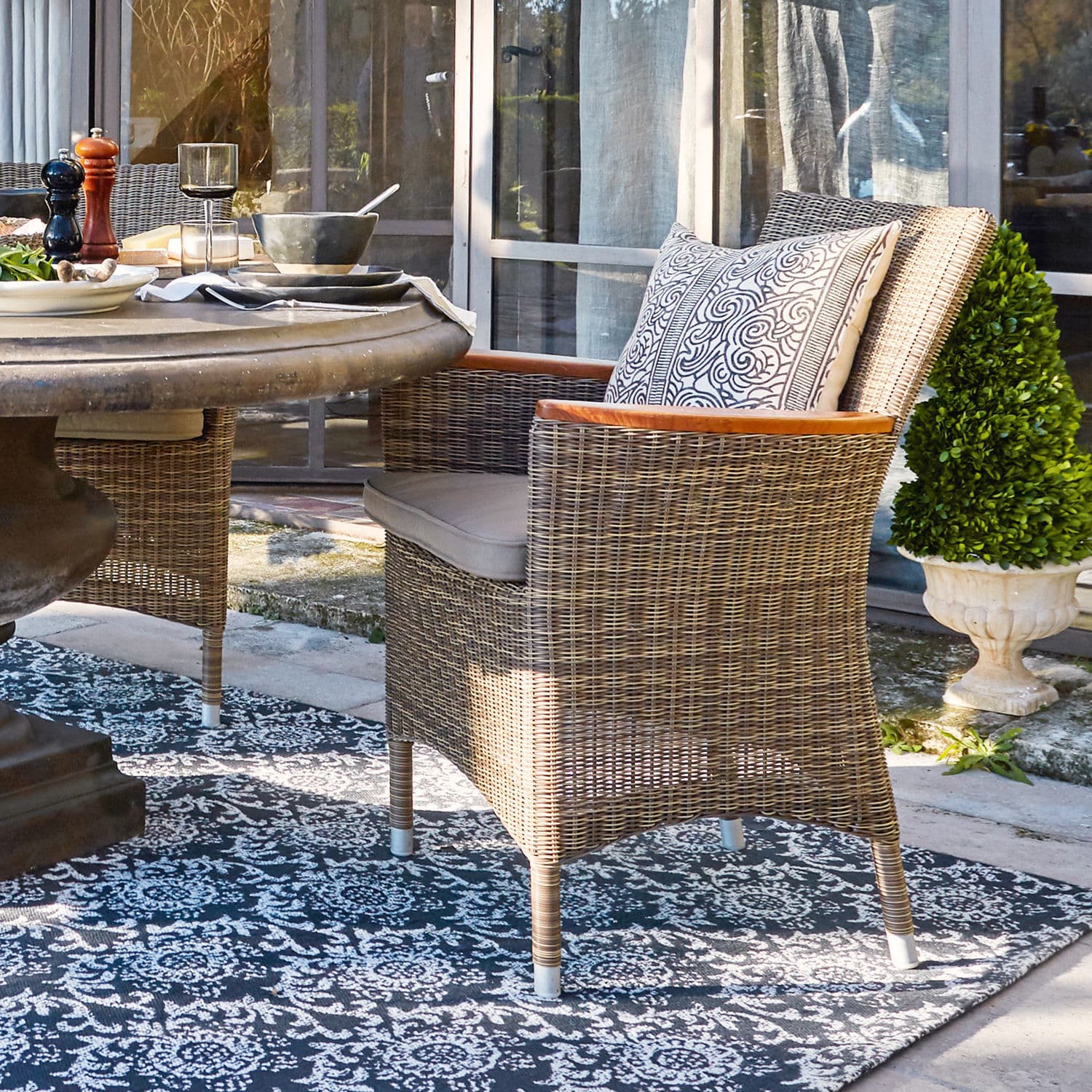 Poltrona Casper Sedia in rattan colore naturale con cuscino e braccioli in legno su terrazza