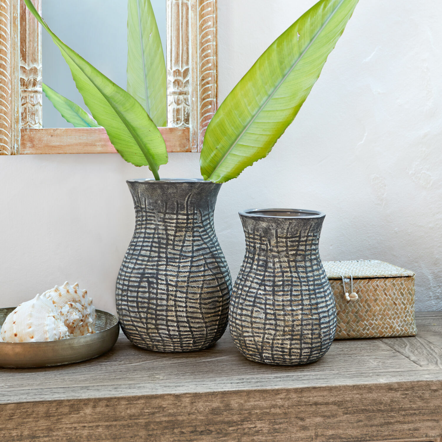 Coppia di vasi Fahrid Due vasi in ceramica grigia con motivo strutturato su tavolo in legno con foglie verdi