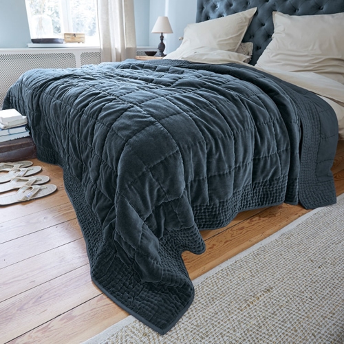 Coperta trapuntata grigio scuro in tessuto morbido su letto in camera luminosa, decorazione casa