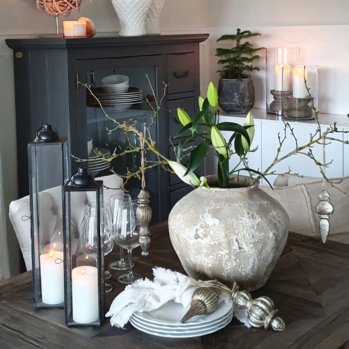 Tavolo decorativo con grande vaso in ceramica beige e candele in lanterne di vetro