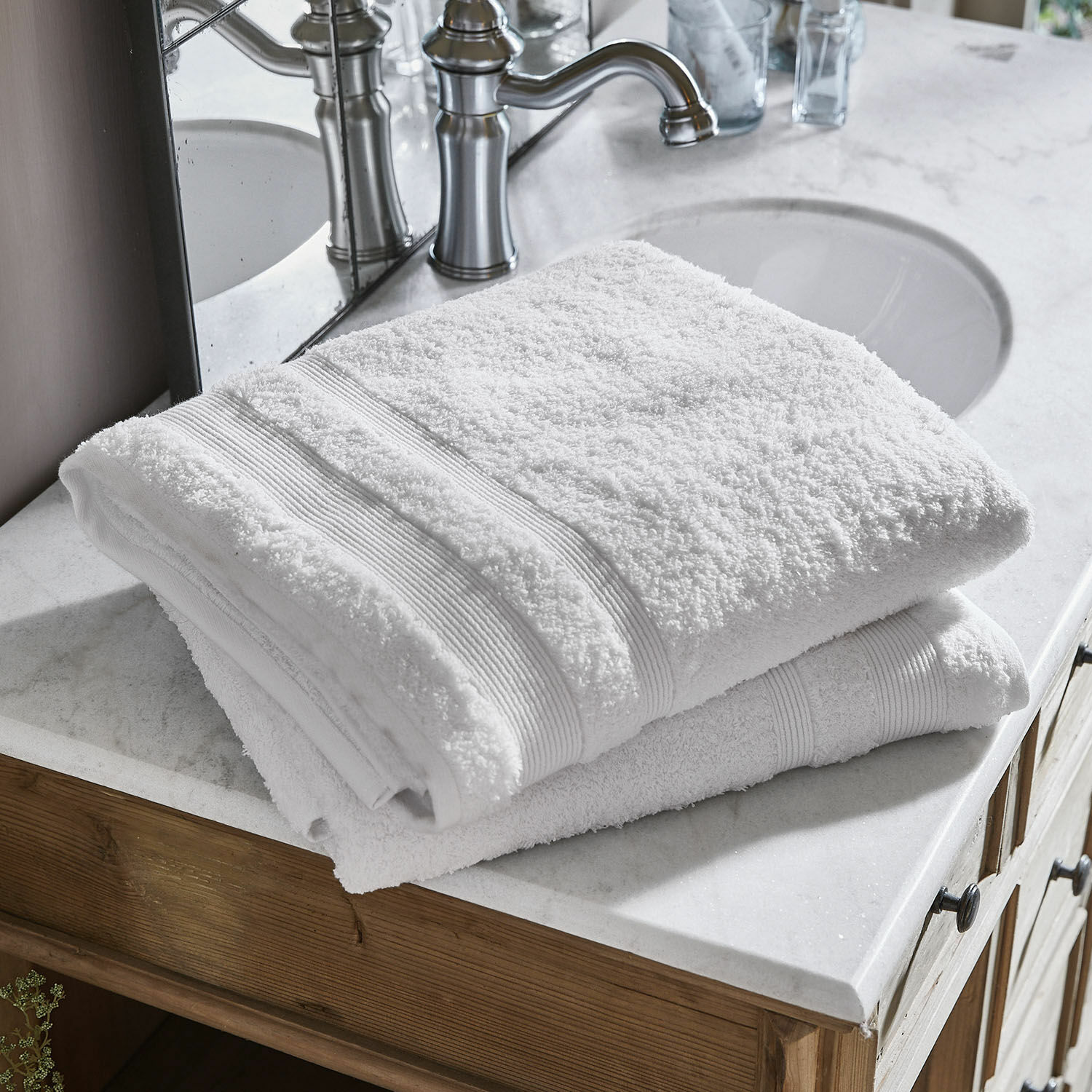 Coppia di teli da bagno Bourogne Asciugamani bianchi in cotone piegati su lavabo in marmo con mobile in legno in bagno