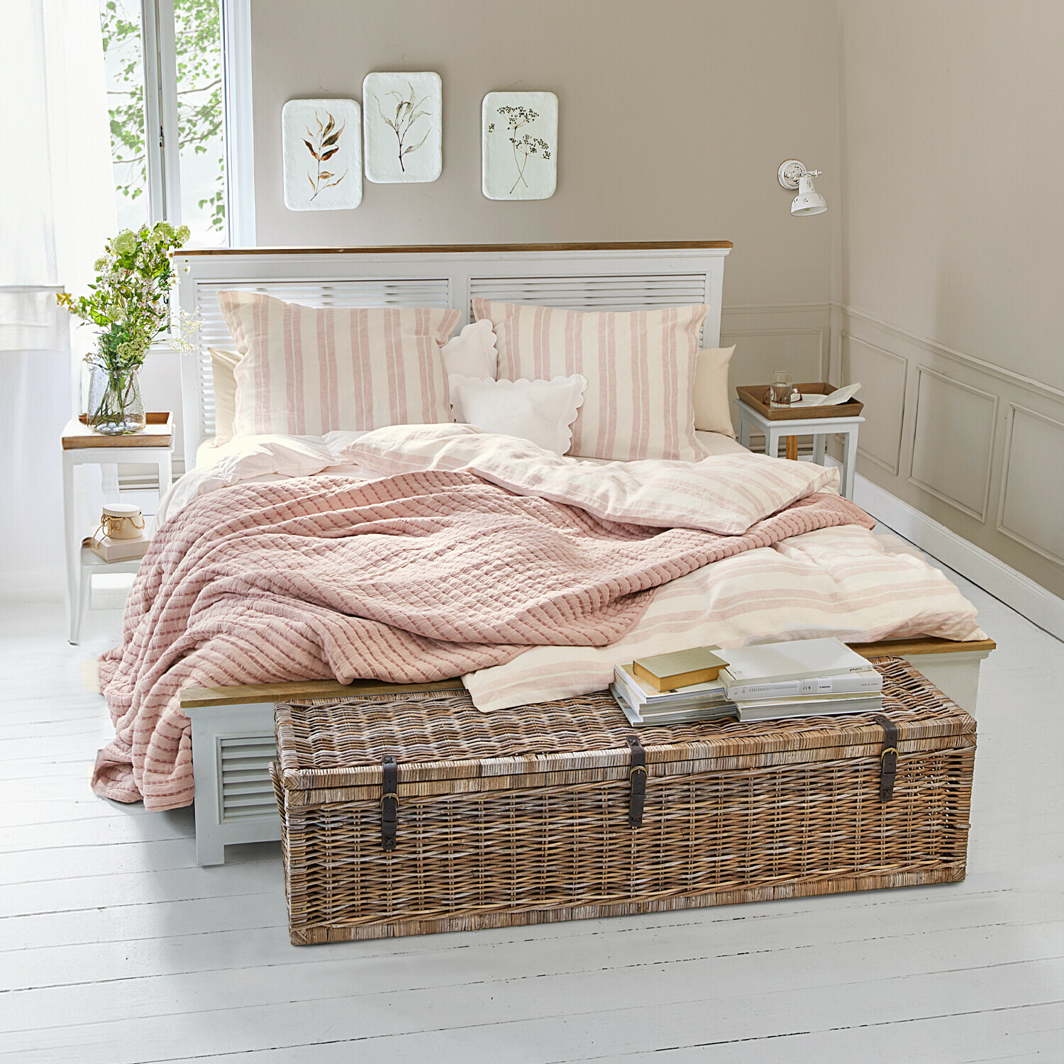 Letto Antje Camera accogliente con letto a righe rosa chiaro e baule in vimini su pavimento bianco